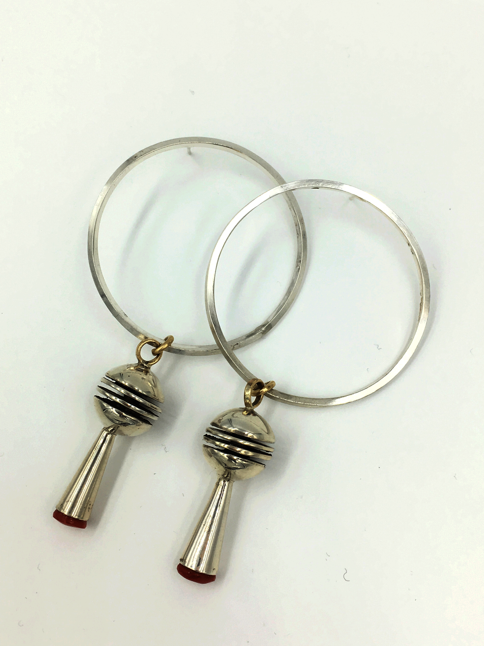 A pair of silver hoop earrings against a white background, laid out so that the hoops overlap. Their bases both feature attached silver spheres with a long silver cone.