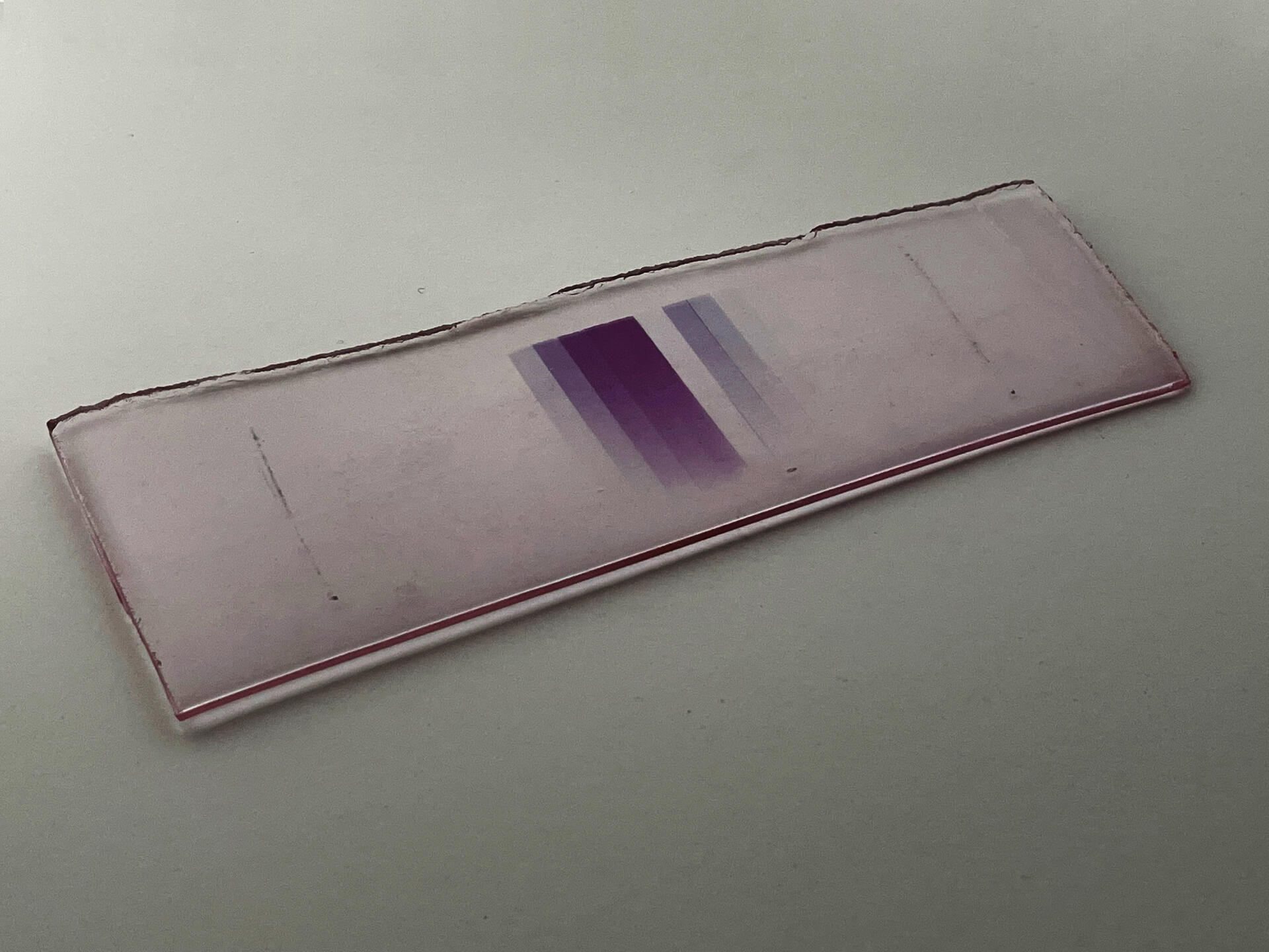 A piece of glass with a gradient of purple lines at its center.
