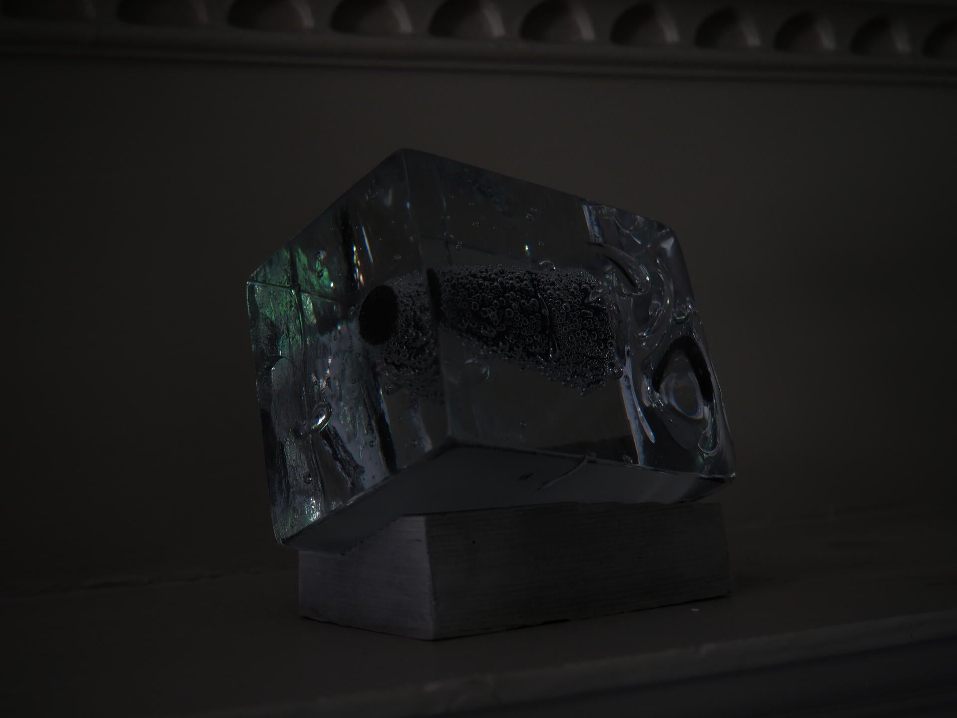 Bubble covered cone encased in glass on a fireplace mantle.