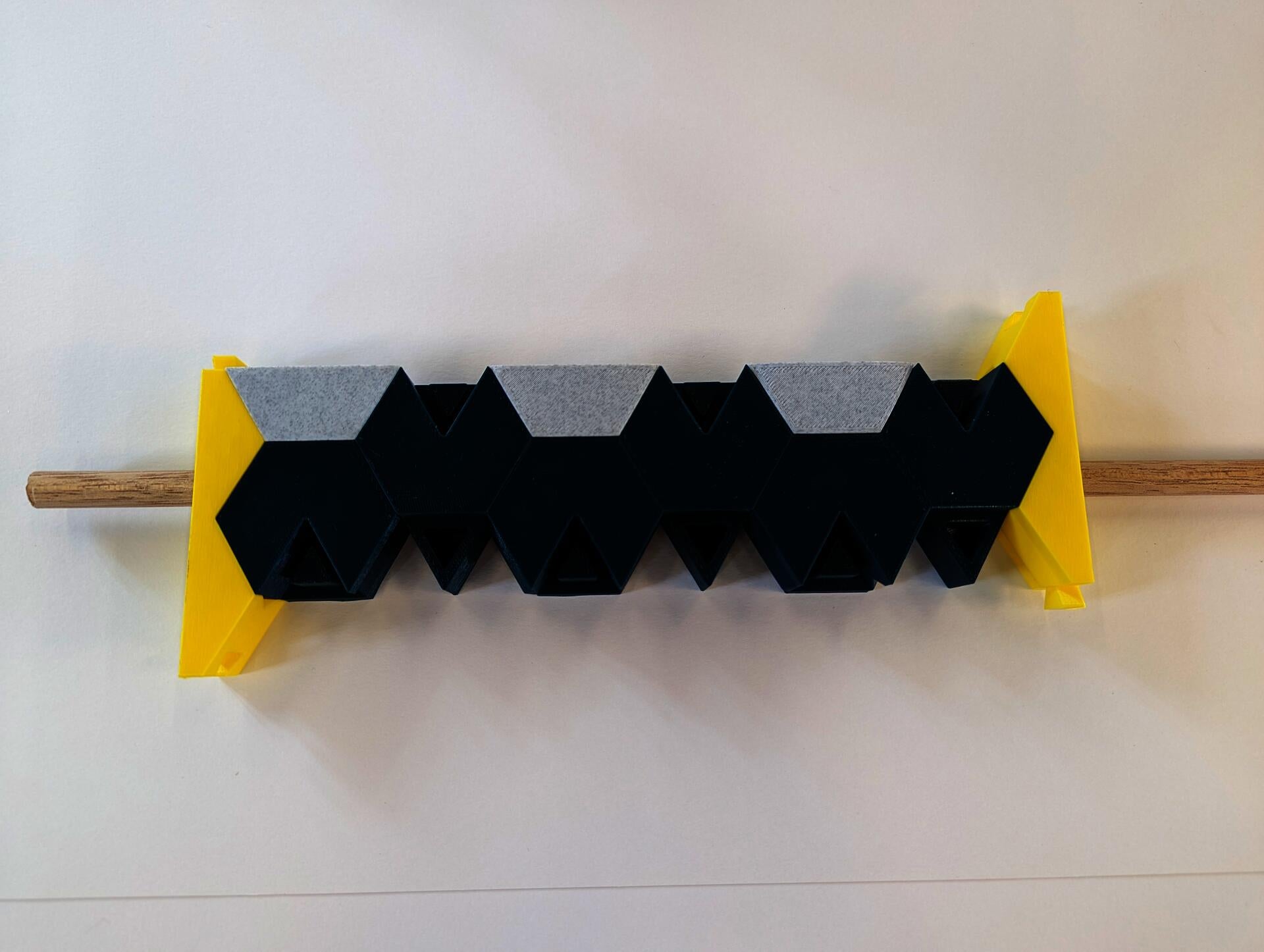 Three hexagon based shapes are pushed together hiding the wooden dowel.