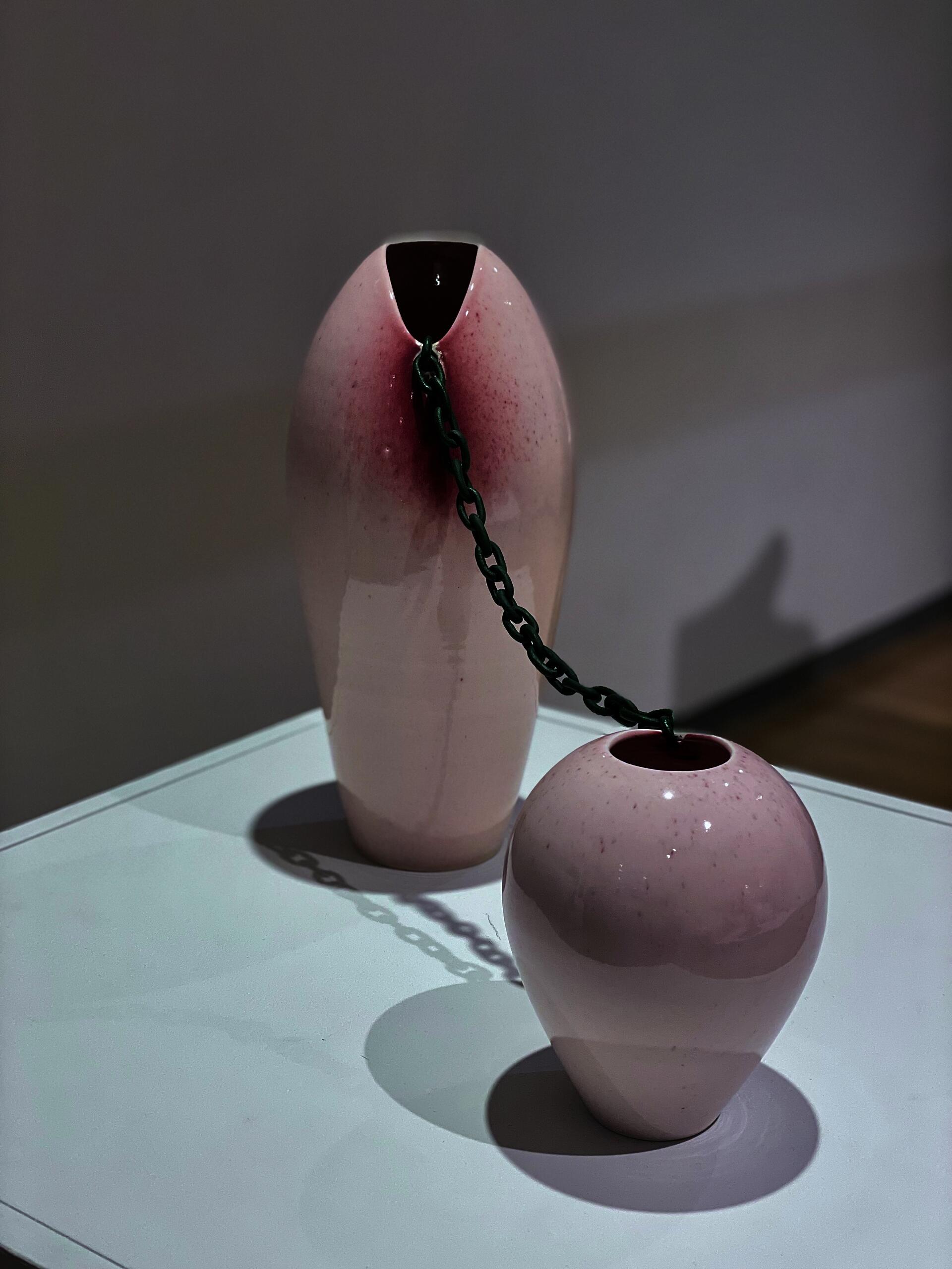 Two vases are connected by a hand-sculpted ceramic chain.