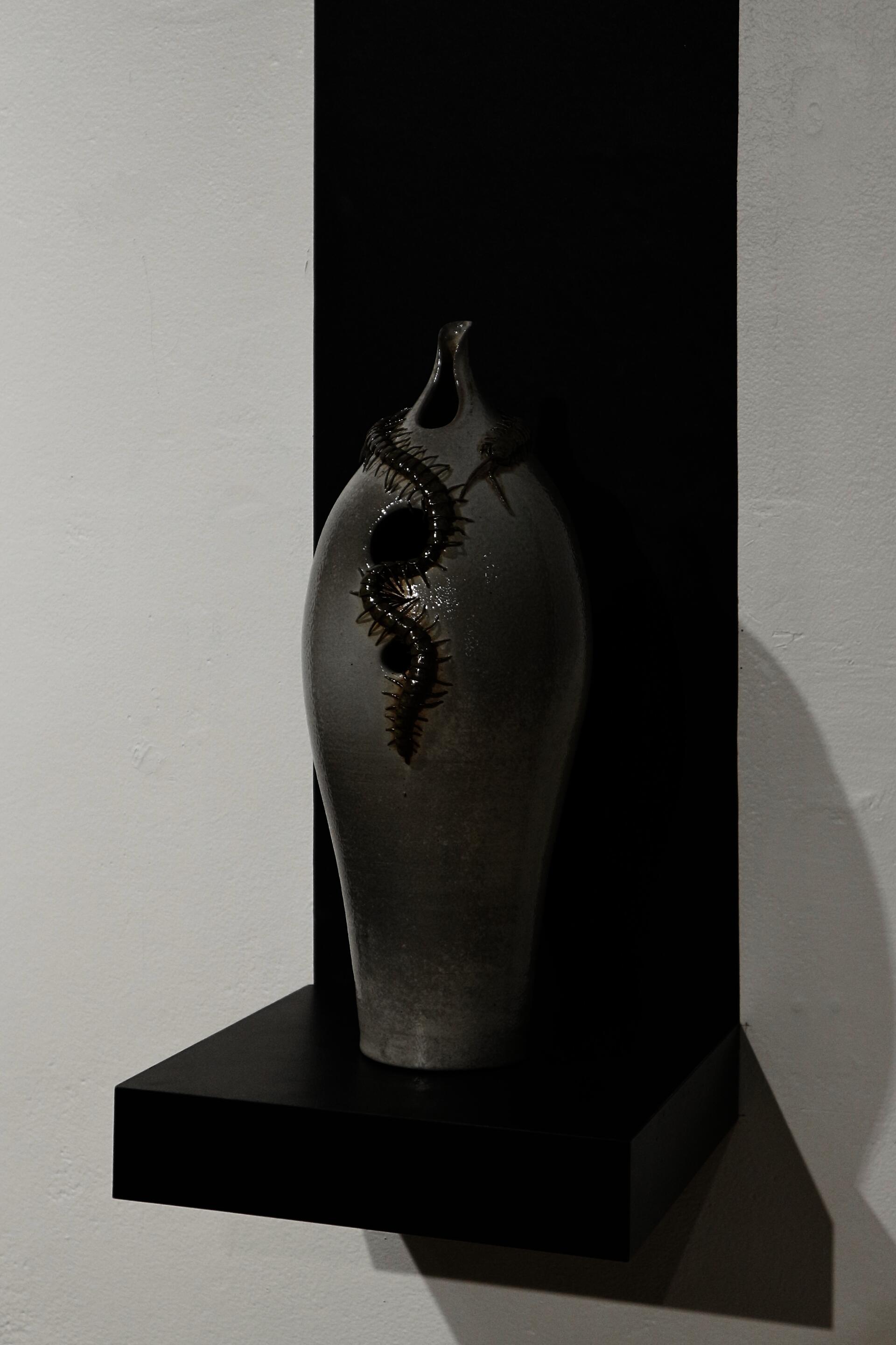 Soda-fired ceramic vessel with a hand-sculpted centipede around the neck.