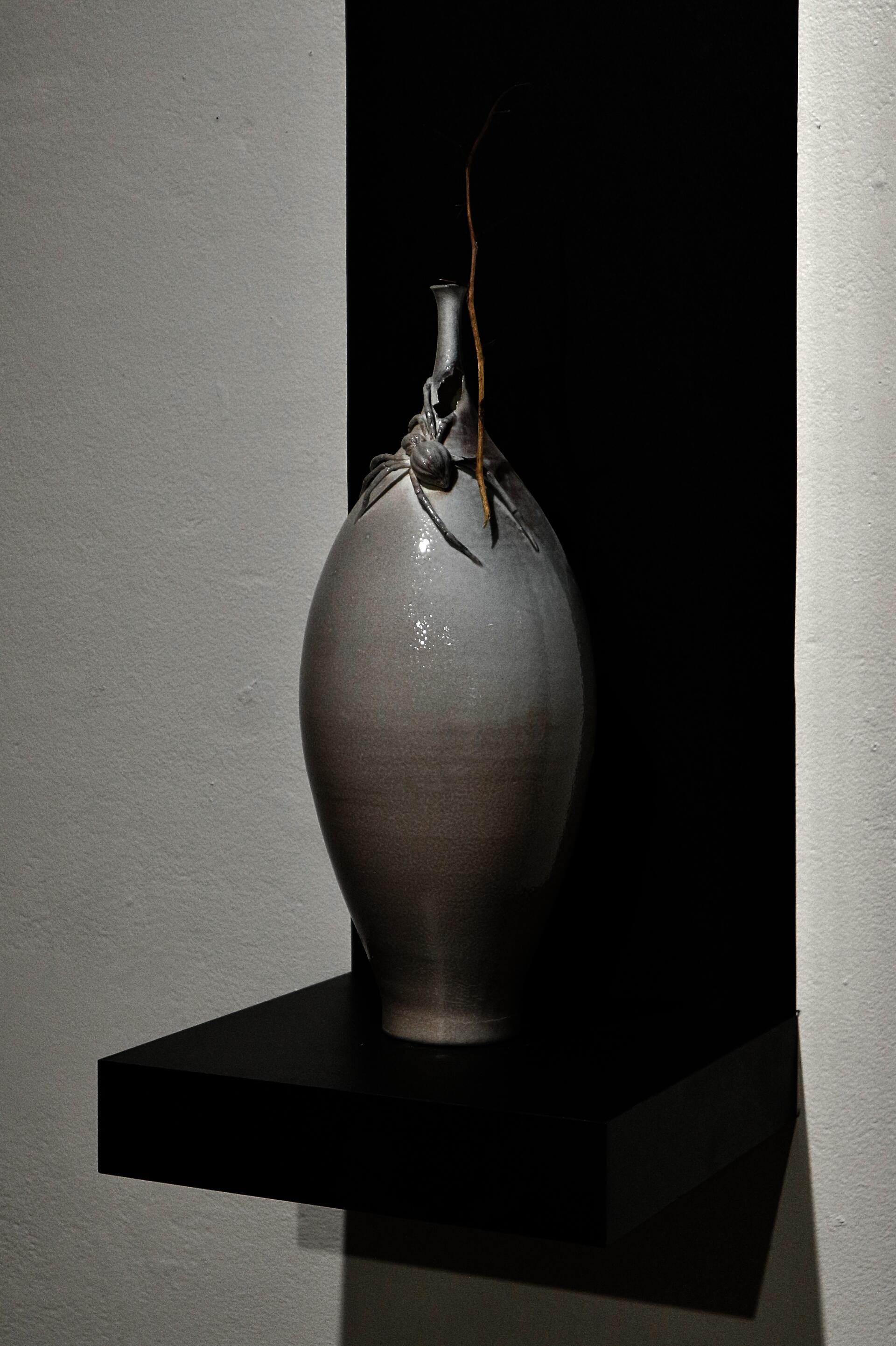 Soda-fired ceramic vessel with hand-sculpted spider around the neck.