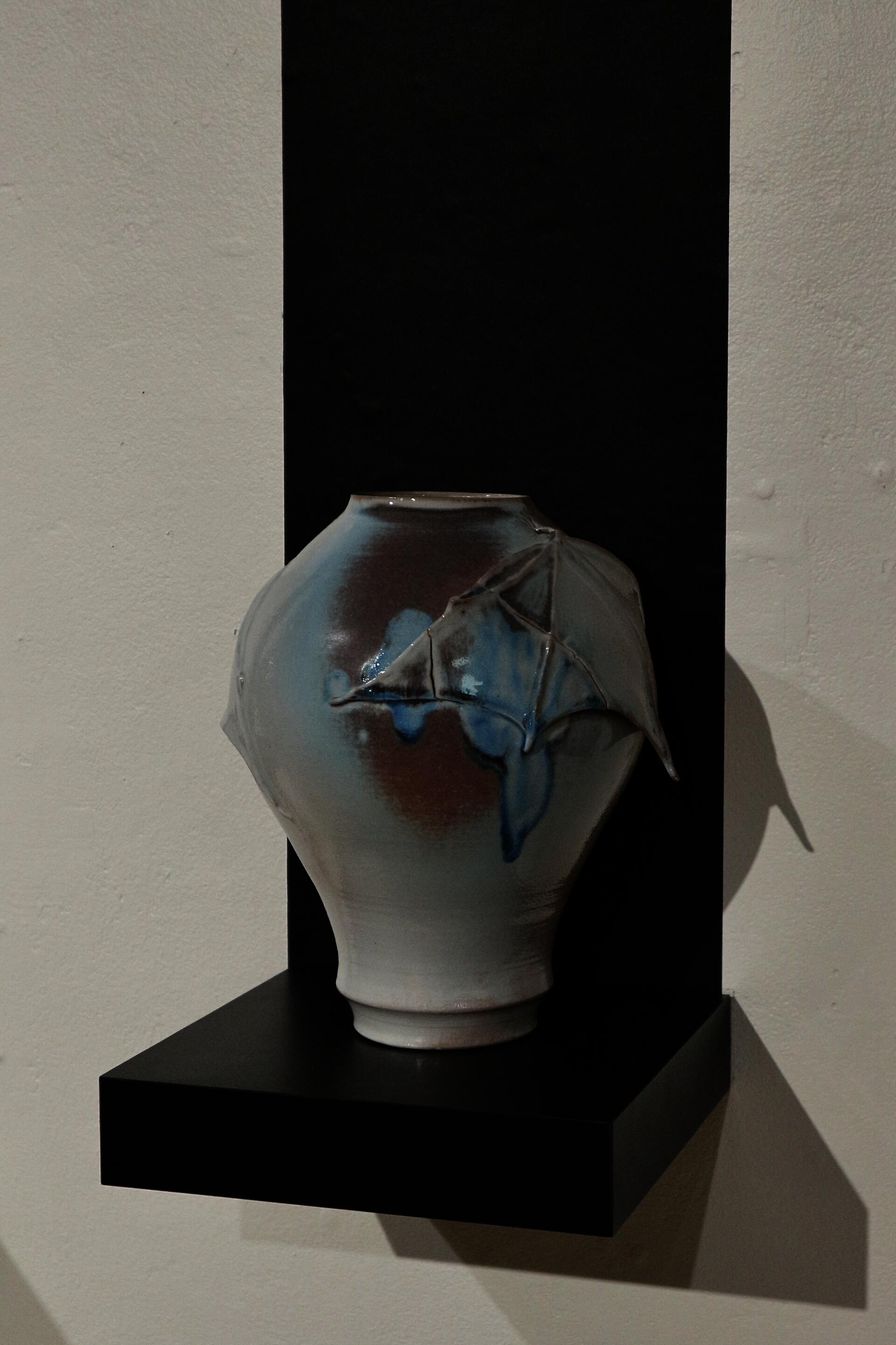 Soda-fired ceramic vessel with a hand-sculpted bat around the neck.