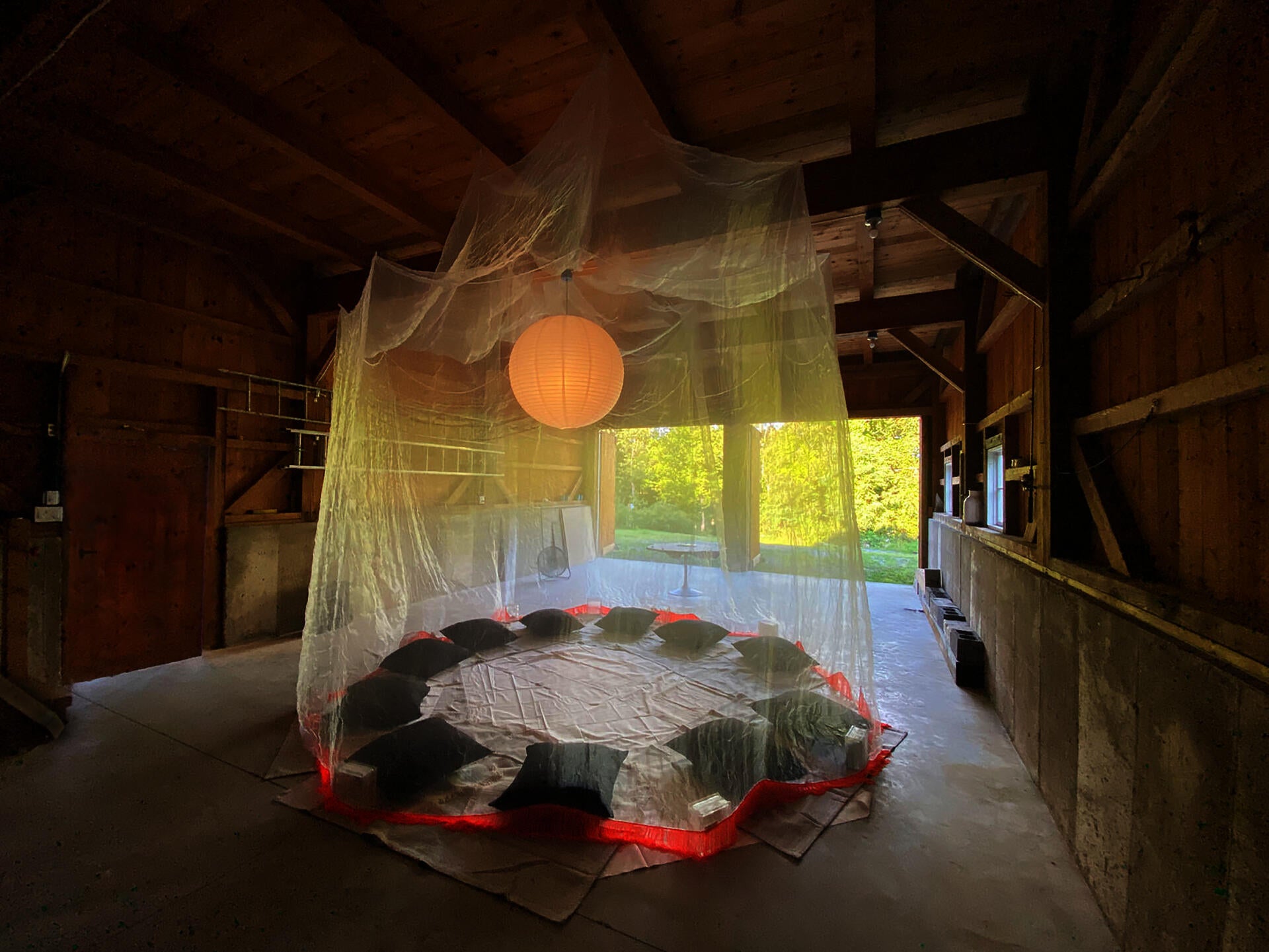 The interior of a barn with a large circular mosquito net hanging from the ceiling