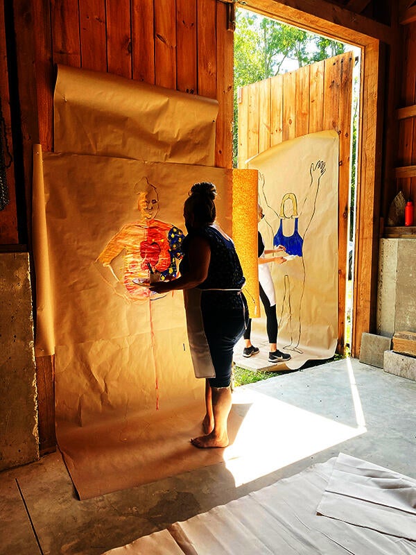 A woman painting a life-sized self portrait.