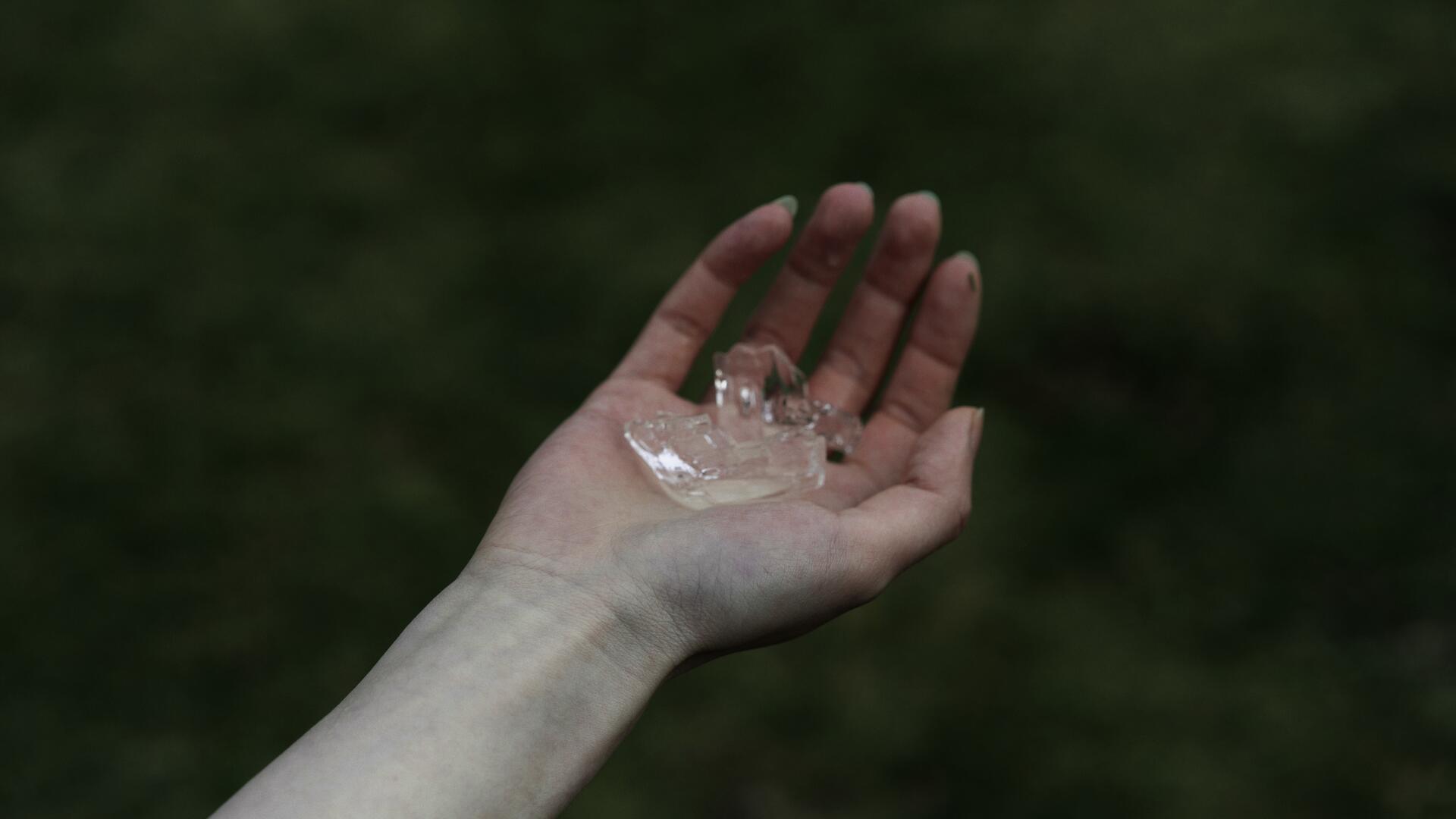 One hand holding a fragment of an ice lens.