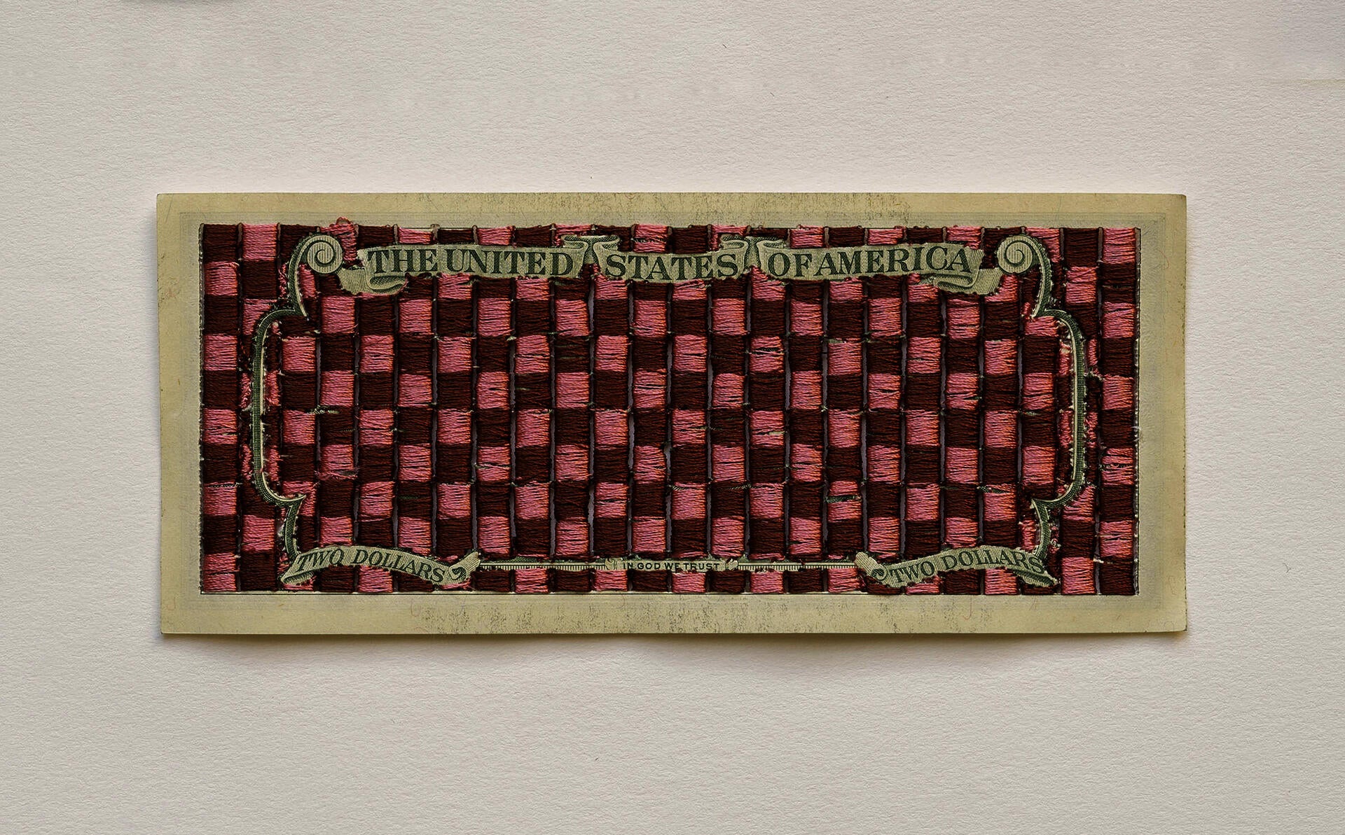 Two dollar bill that has checkered pattern embroidered onto it