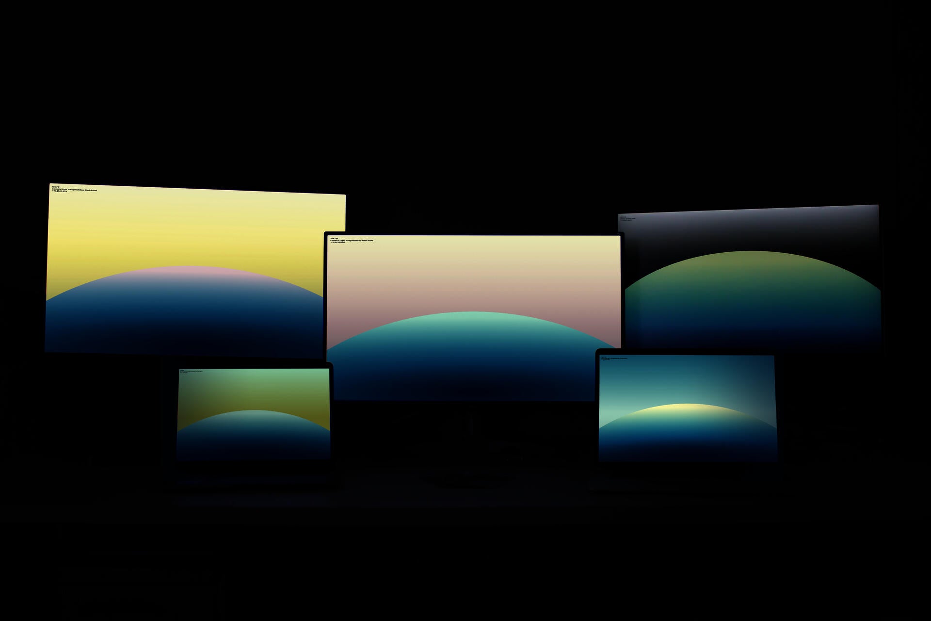 Five computer monitors of different sizes display a colorful screen saver design.