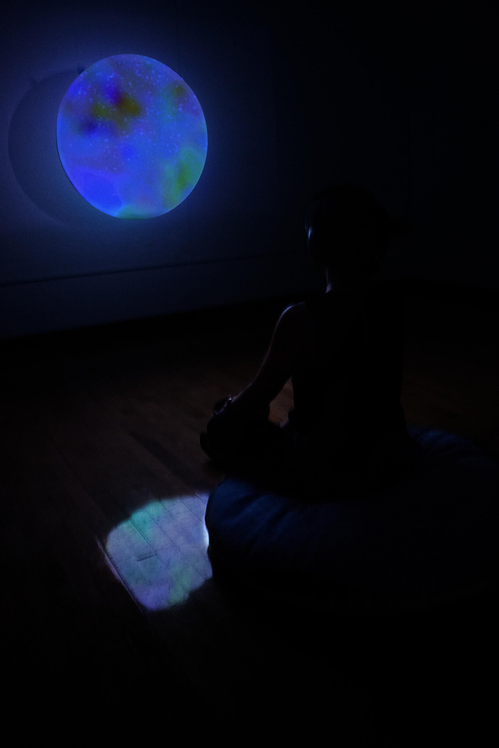 Projected glowing image with person sitting cross-legged in front of screen