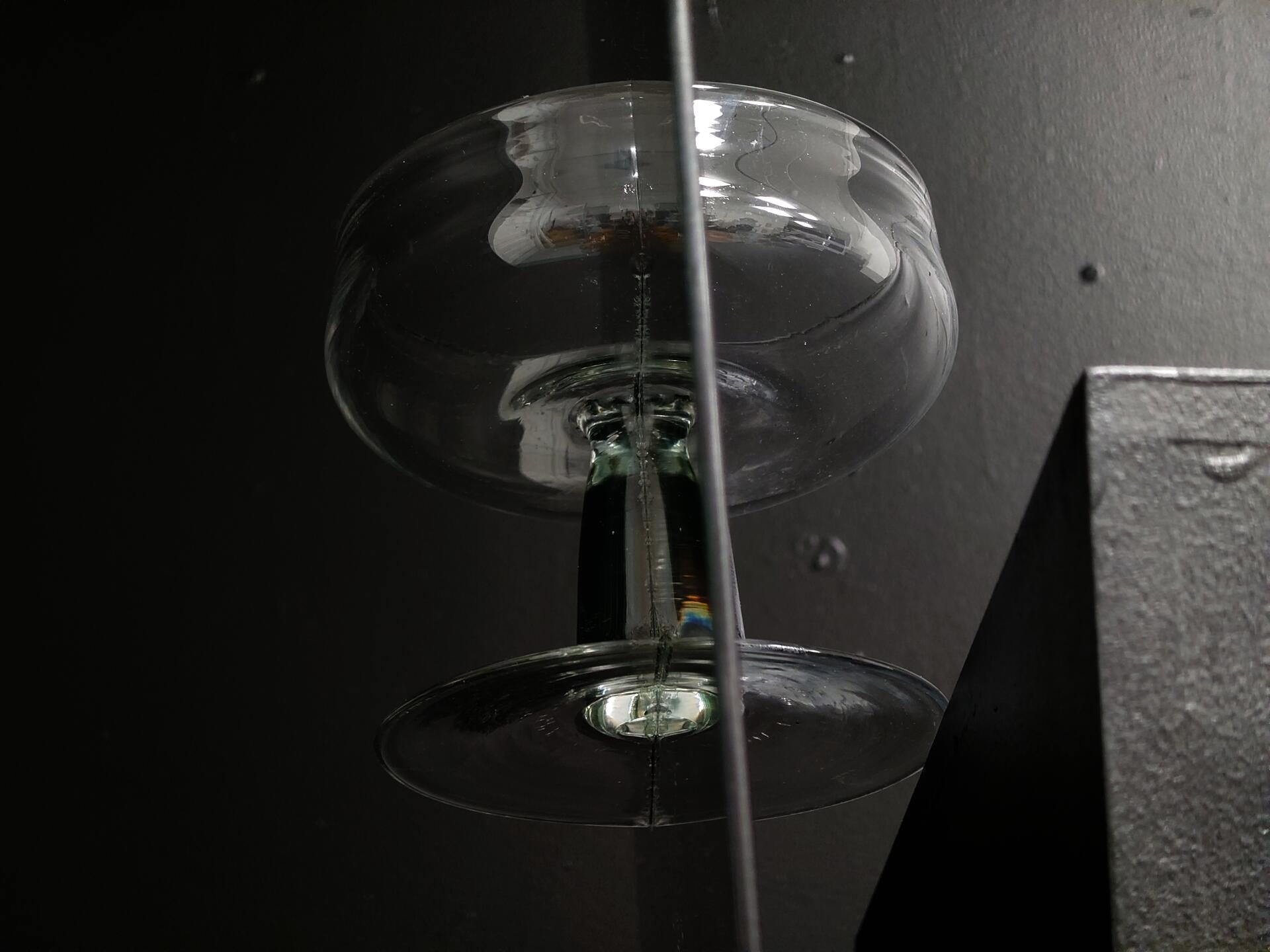 Halves of a hand-blown goblet glued onto each side of a mirror and resting meticulously at the edge of a pedestal.