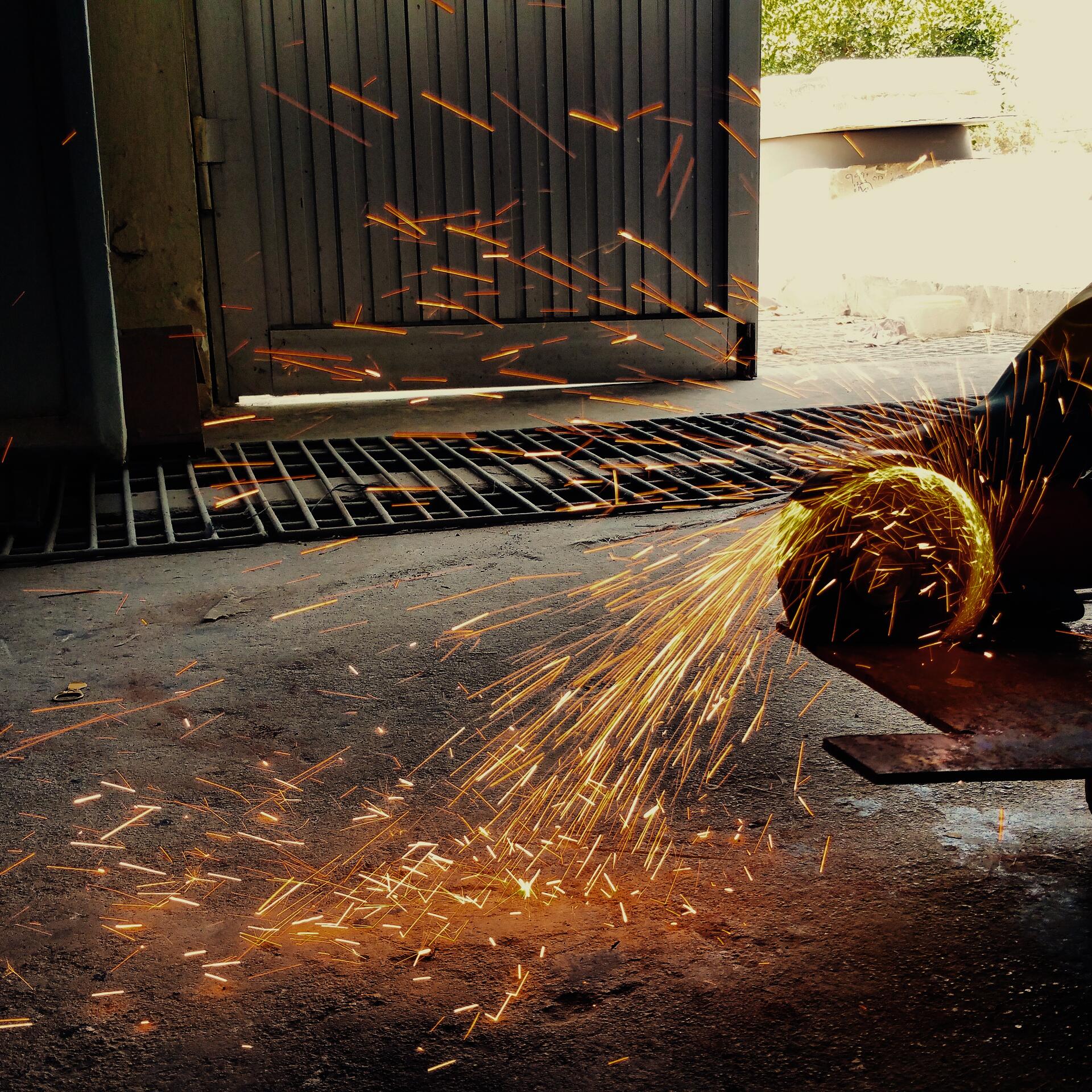 A metal sheet being cut by an angle grinder portraying the element of learning by doing.