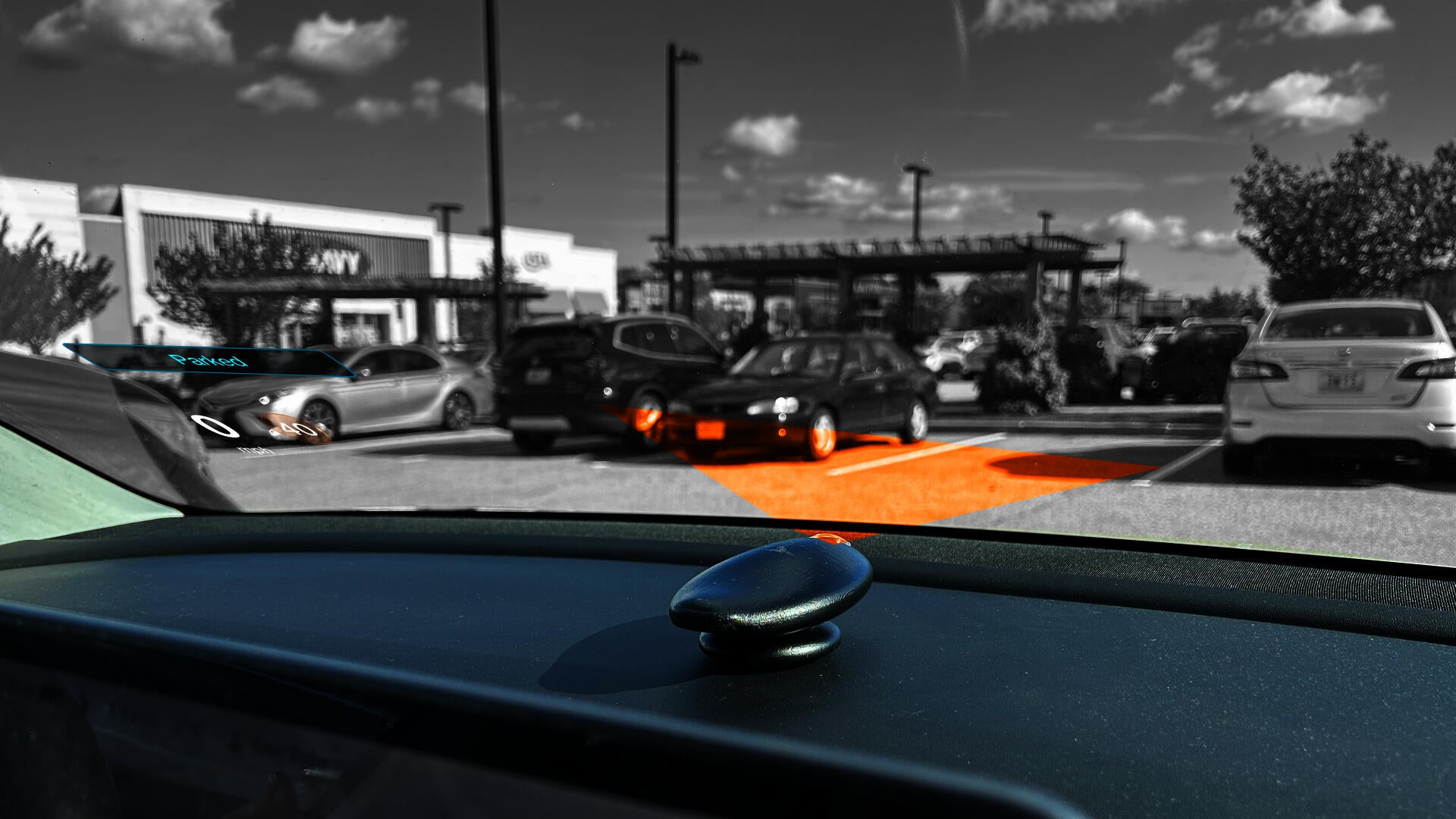 The Orca placed on the dash of a car projecting onto the windshield. The orange represents the projection angle. In the bottom left corner parts of the overall UI can be seen.