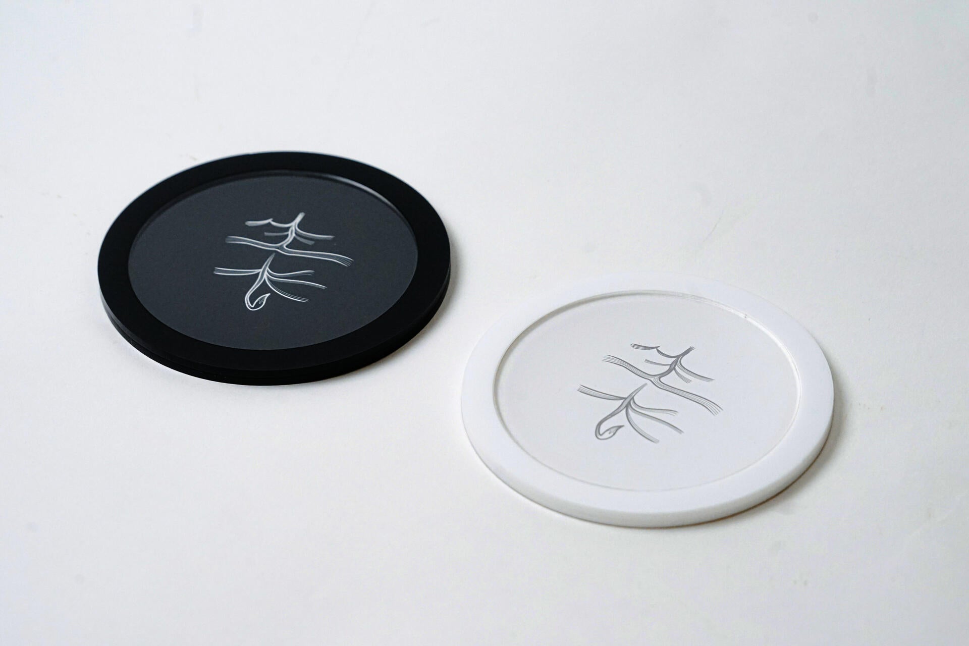 One white and one black cup mat with Chinese letters on it