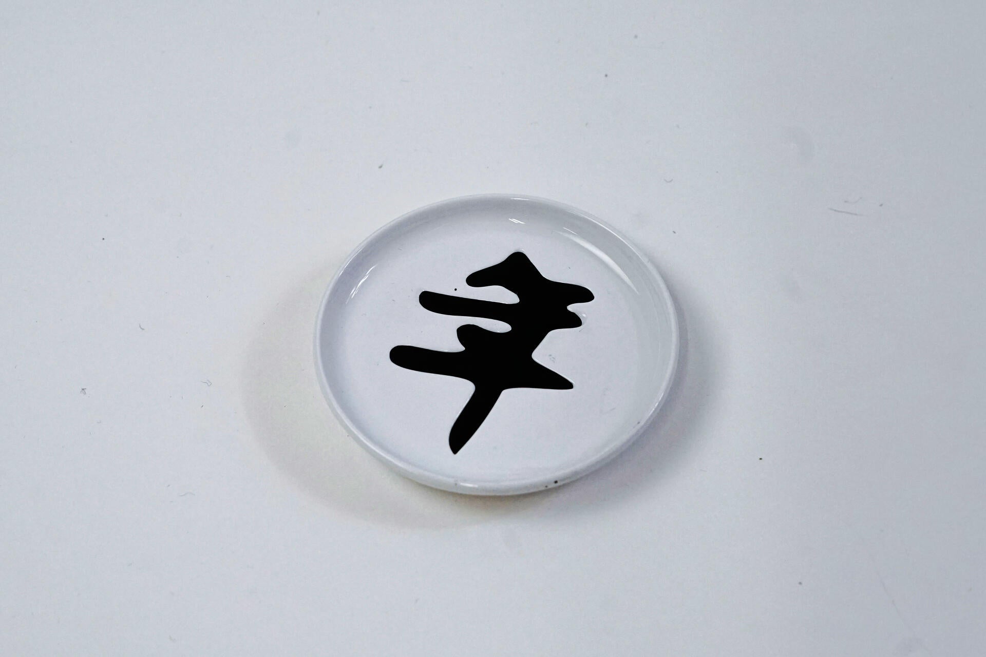 A white dip sauce dish with a black Chinese character in it