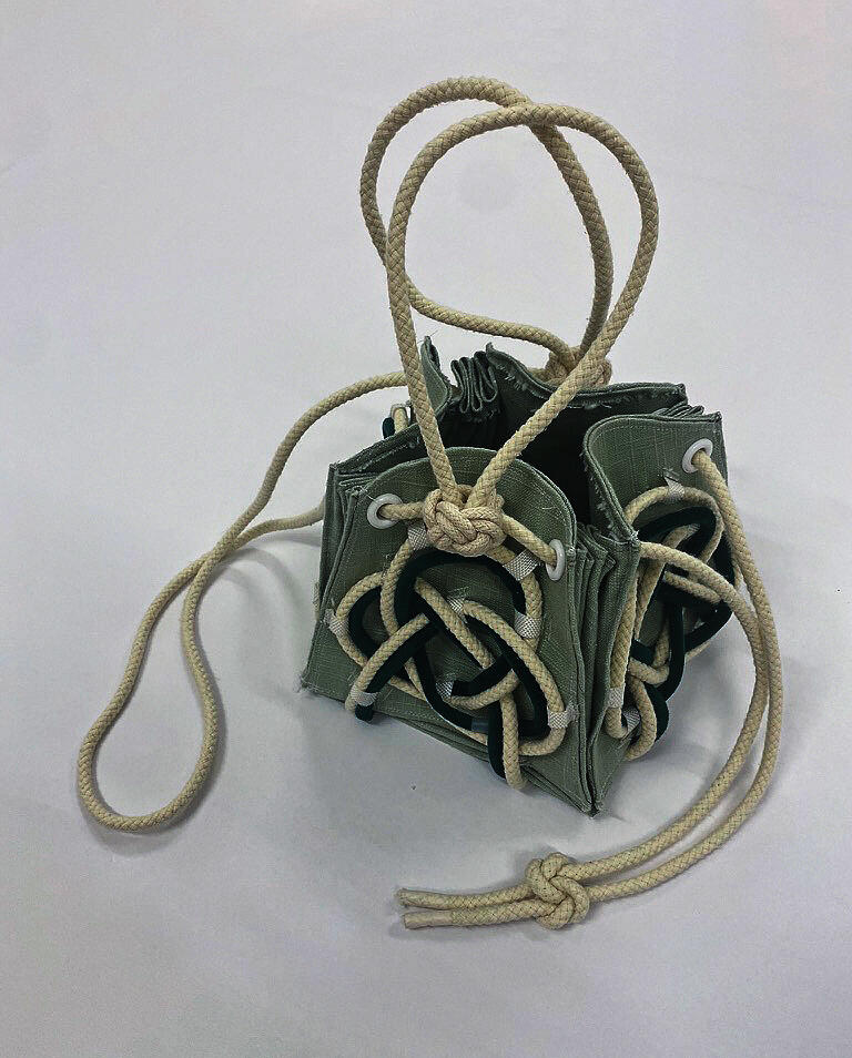 A green cube bag wrapped with cords on a white background