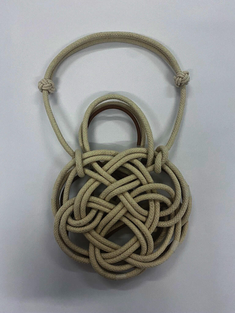 An ivory bag made with cords on a white background