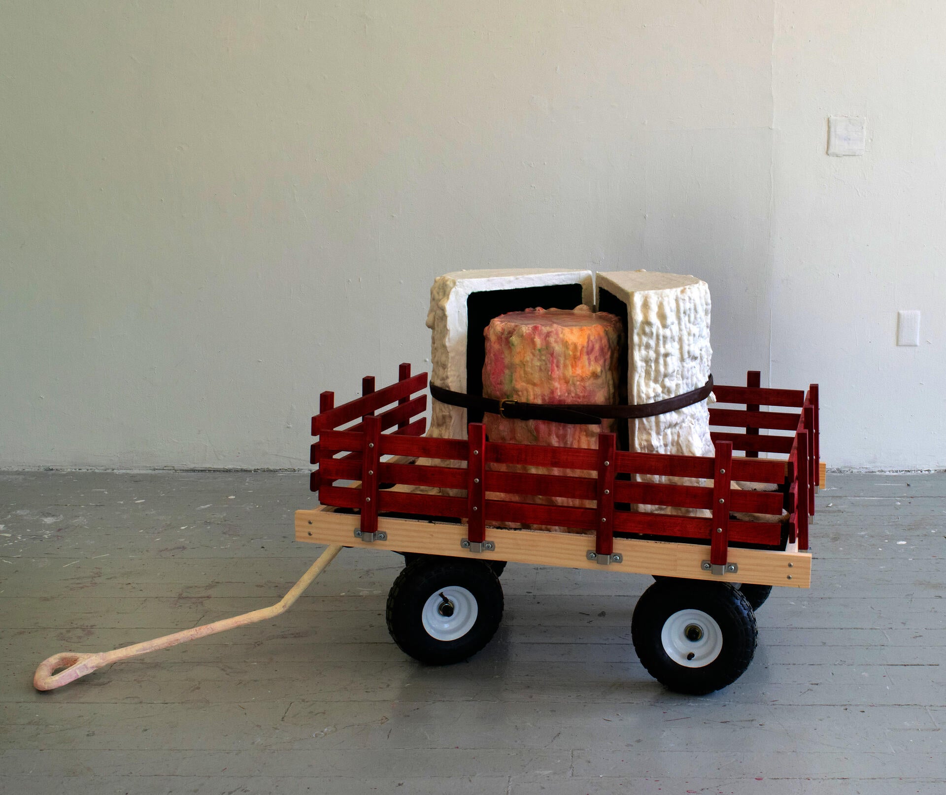 A large fake stump is split open to reveal a smaller, nesting stump, both of which sit in an oversized red wagon