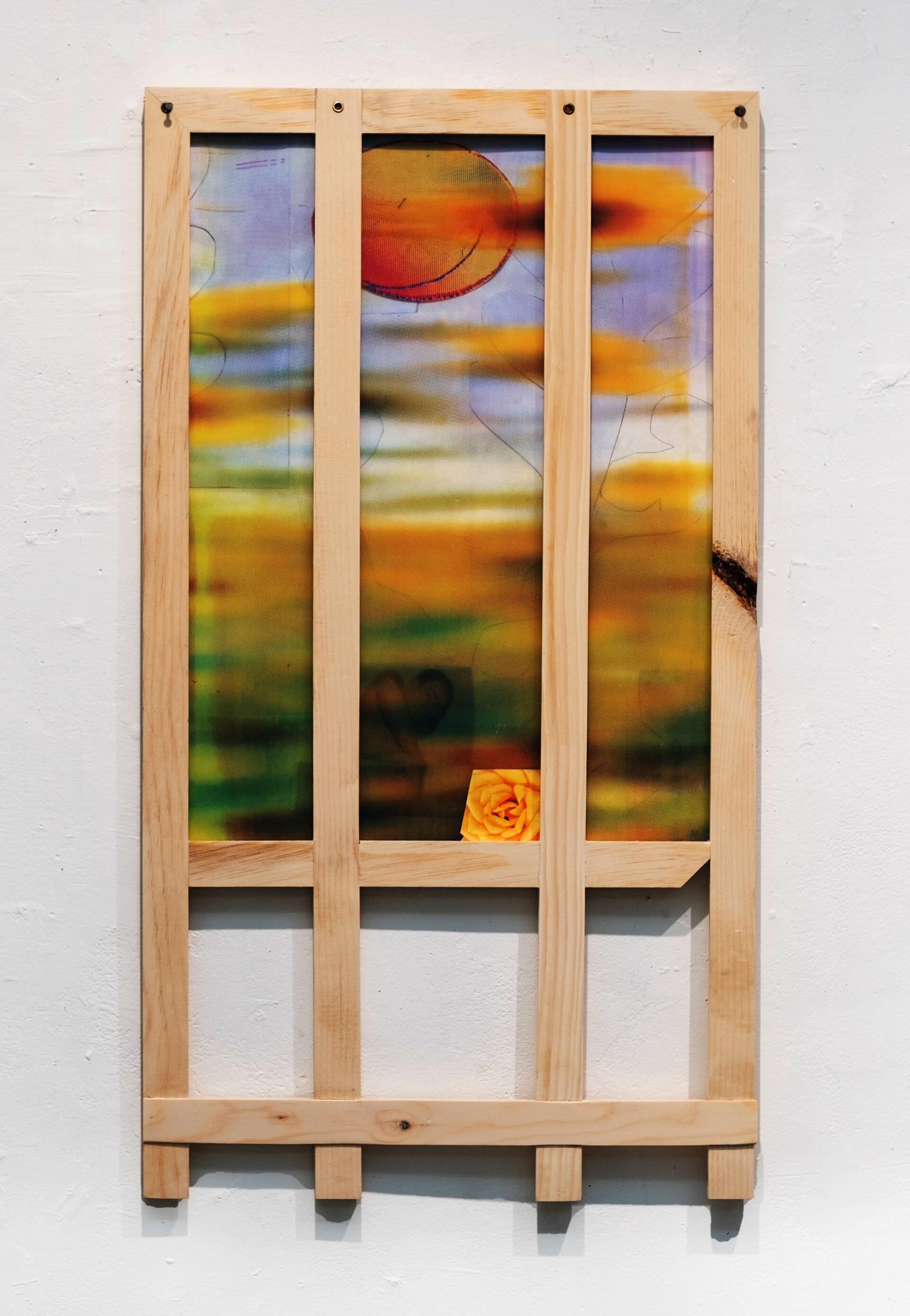 a picket fence-like frame houses a blurry screenprint of yellow flowers
