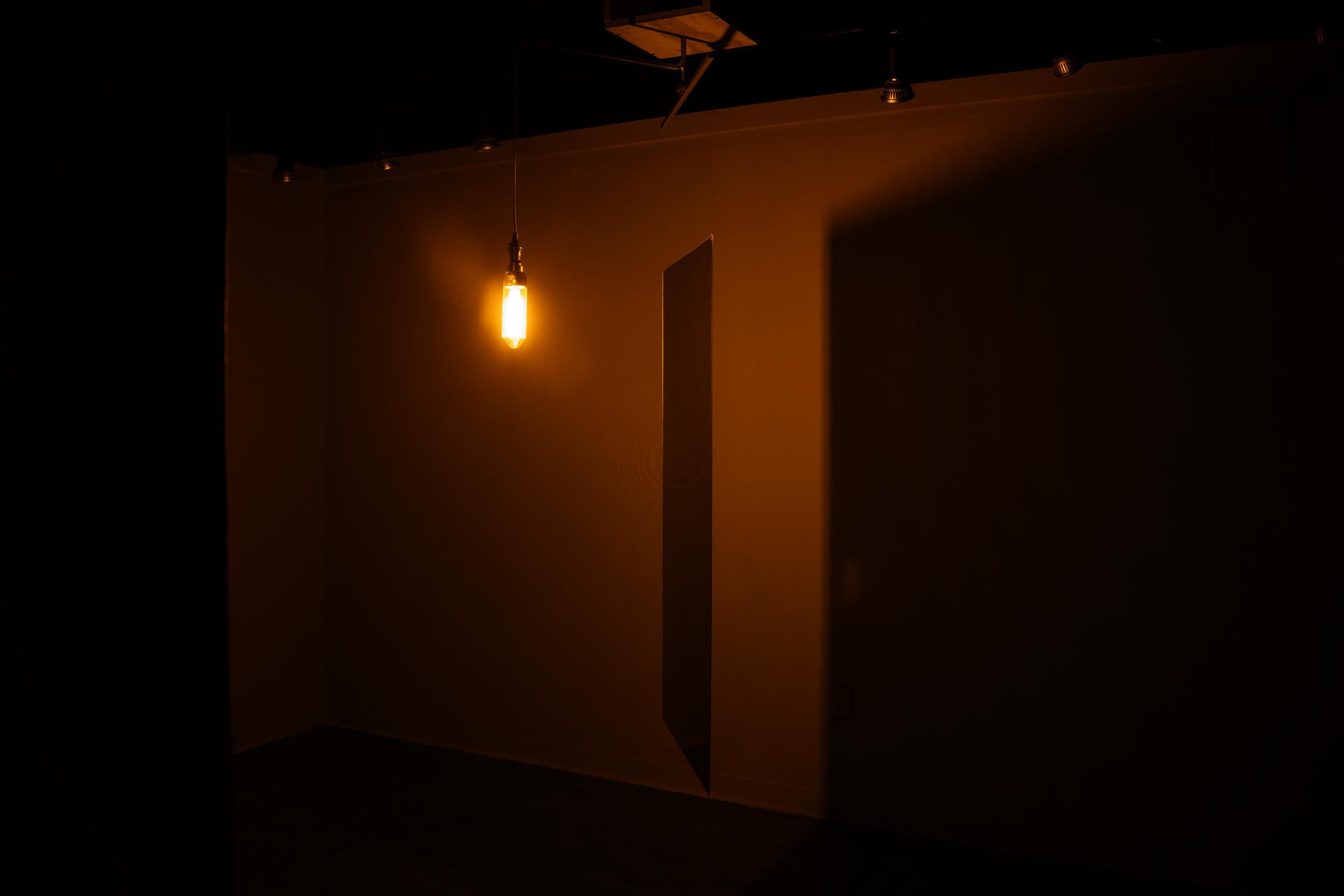 Light bulb in front of a two-way mirror in yellow light.