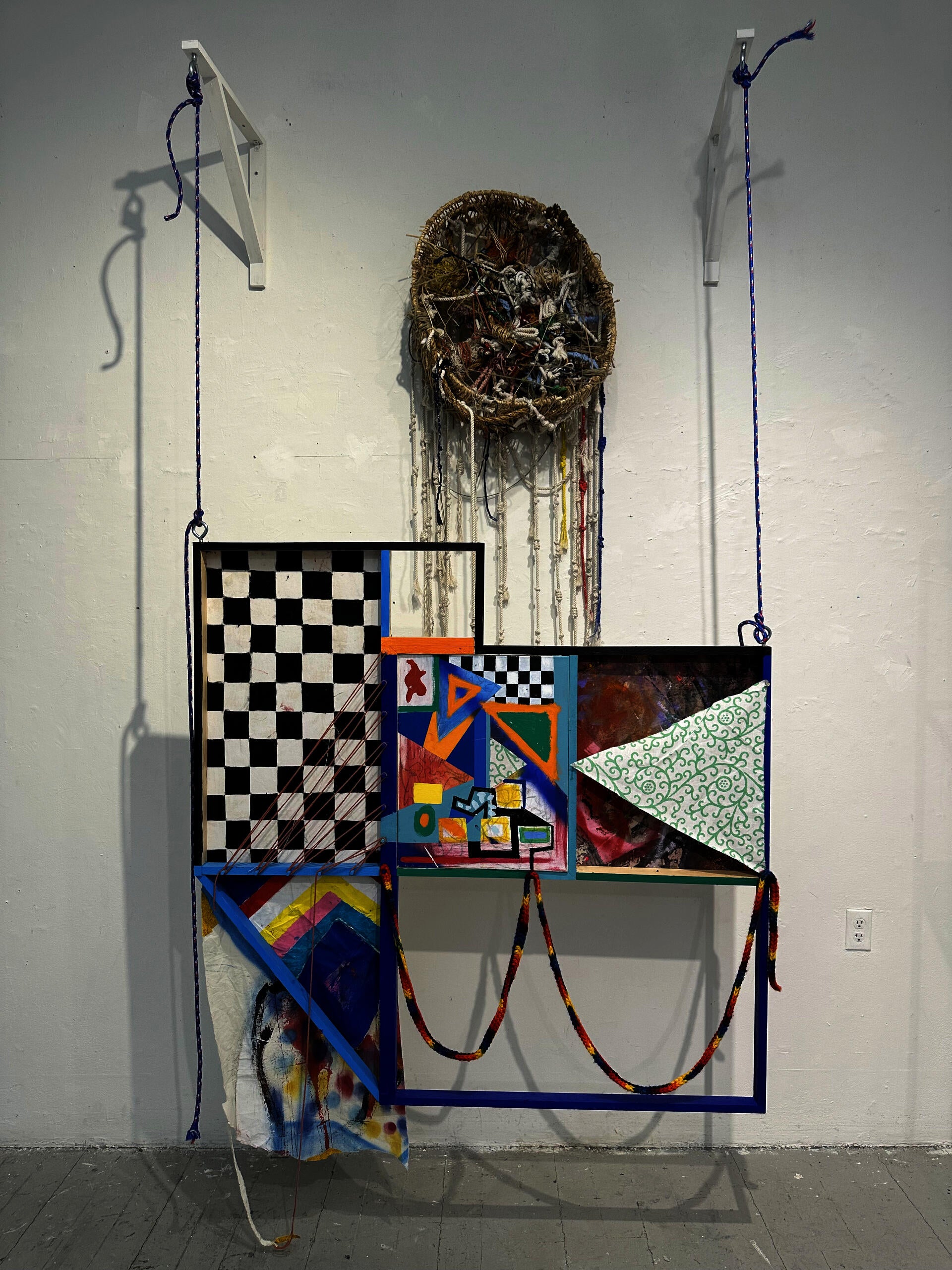 Geometric abstract painting hanging on hooks by rope
