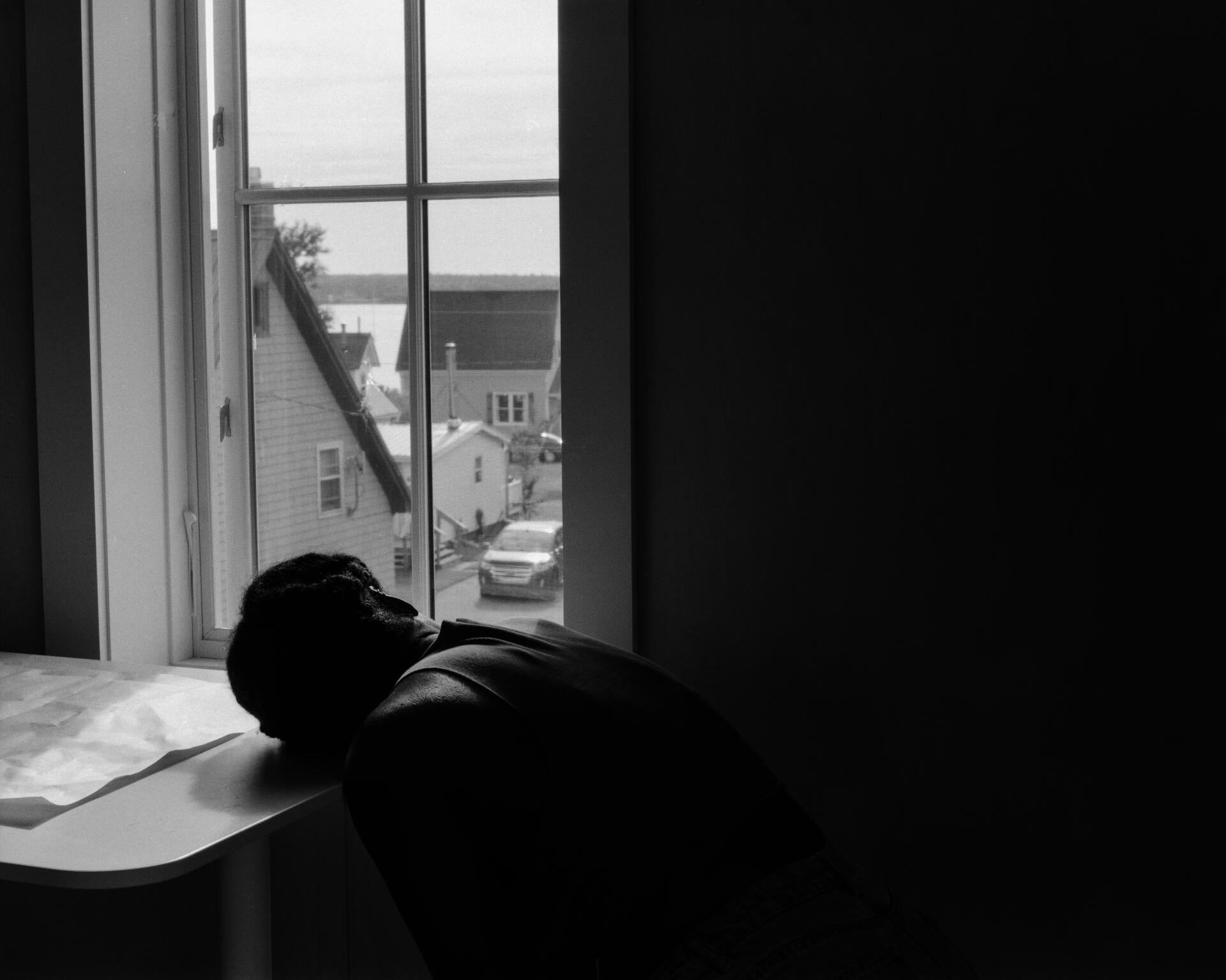 a table is in front a window and a person leans their head over