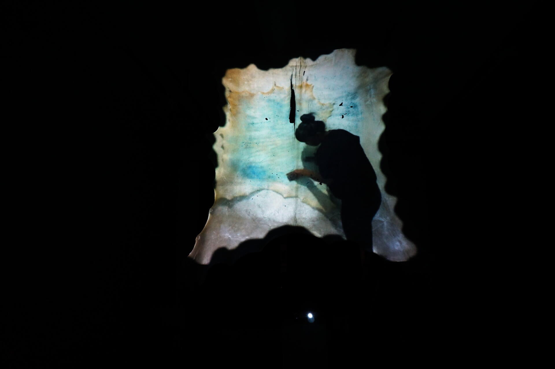 Still of the video projecting on the parchment in the museum setting 