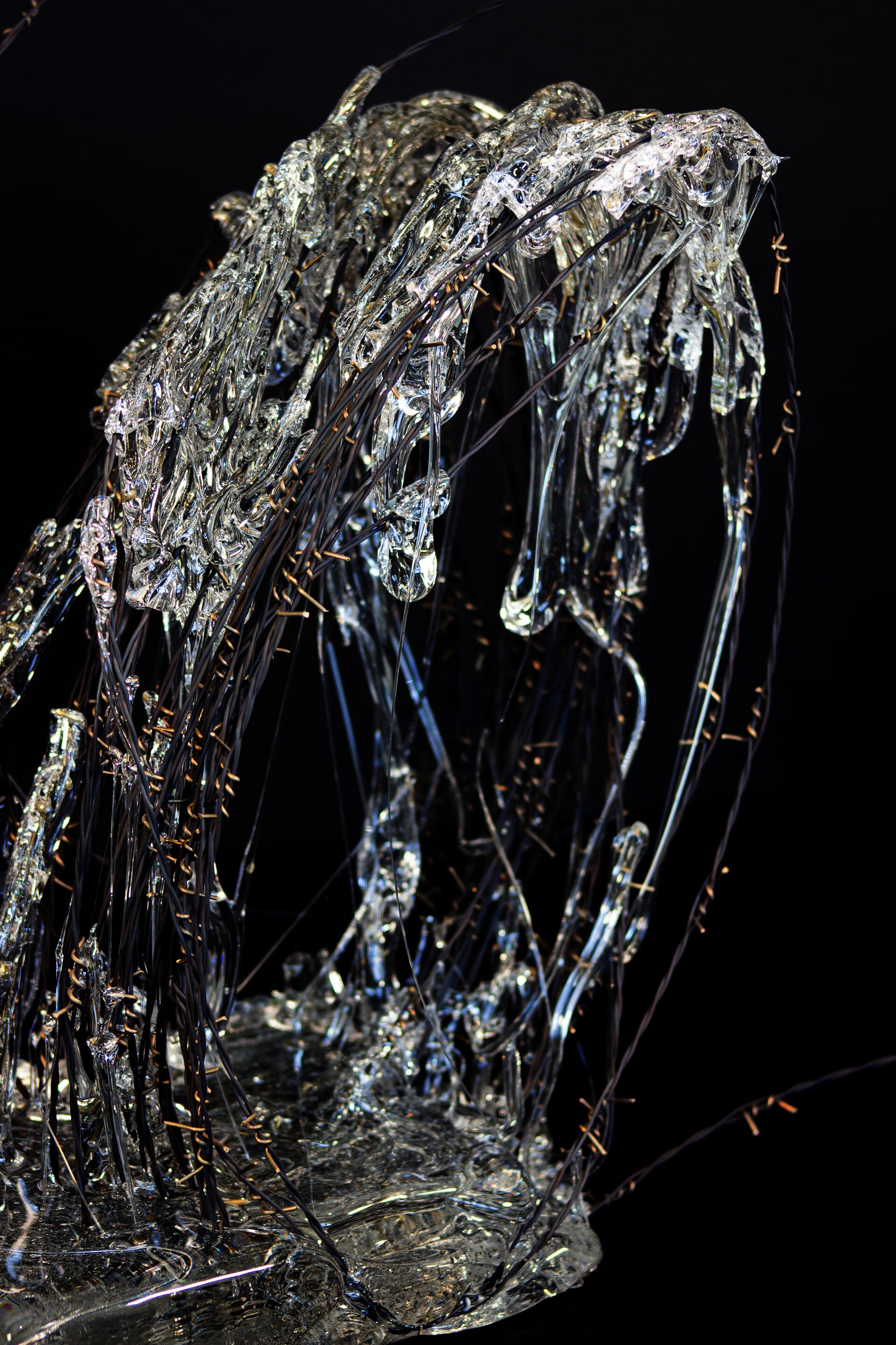 Roll of hand-woven barbed wire with molten glass encasing some parts of it.