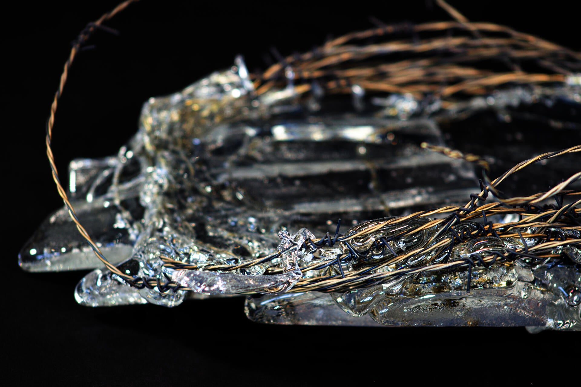 Roll of hand-woven barbed wire with molten glass encasing some parts of it.