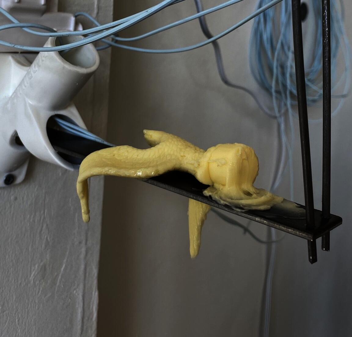 A miniature American eagle - made of butter - droops as it melts atop a steel bar.