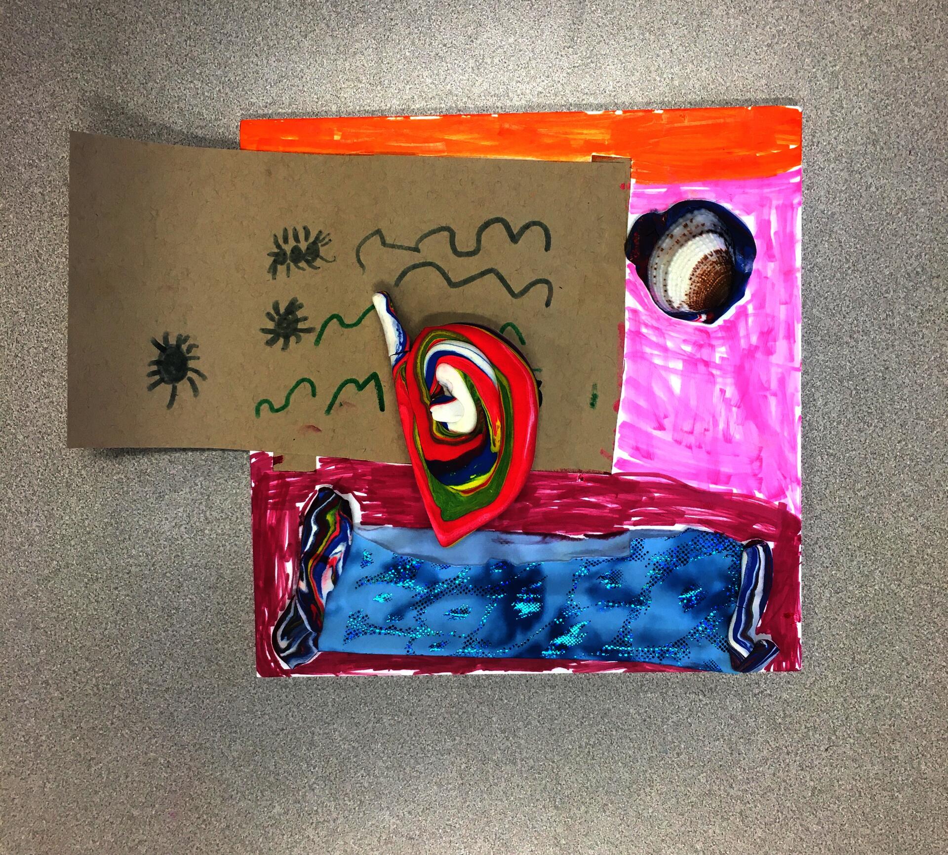 A square piece of white foam core colored with marker in sections of orange, pink, and pinkish red. A shell is attached to the pink section, sitting on a blob of dark blue and red air-dry clay. A sparkly blue piece of stretch fabric is affixed to the pinkish red section with two strips of color-swirled air-dry clay on either end of the fabric. A rectangular piece of cardboard covers a large portion of the foam core and extends beyond the left side. The cardboard has squiggly lines and insects drawn on it in