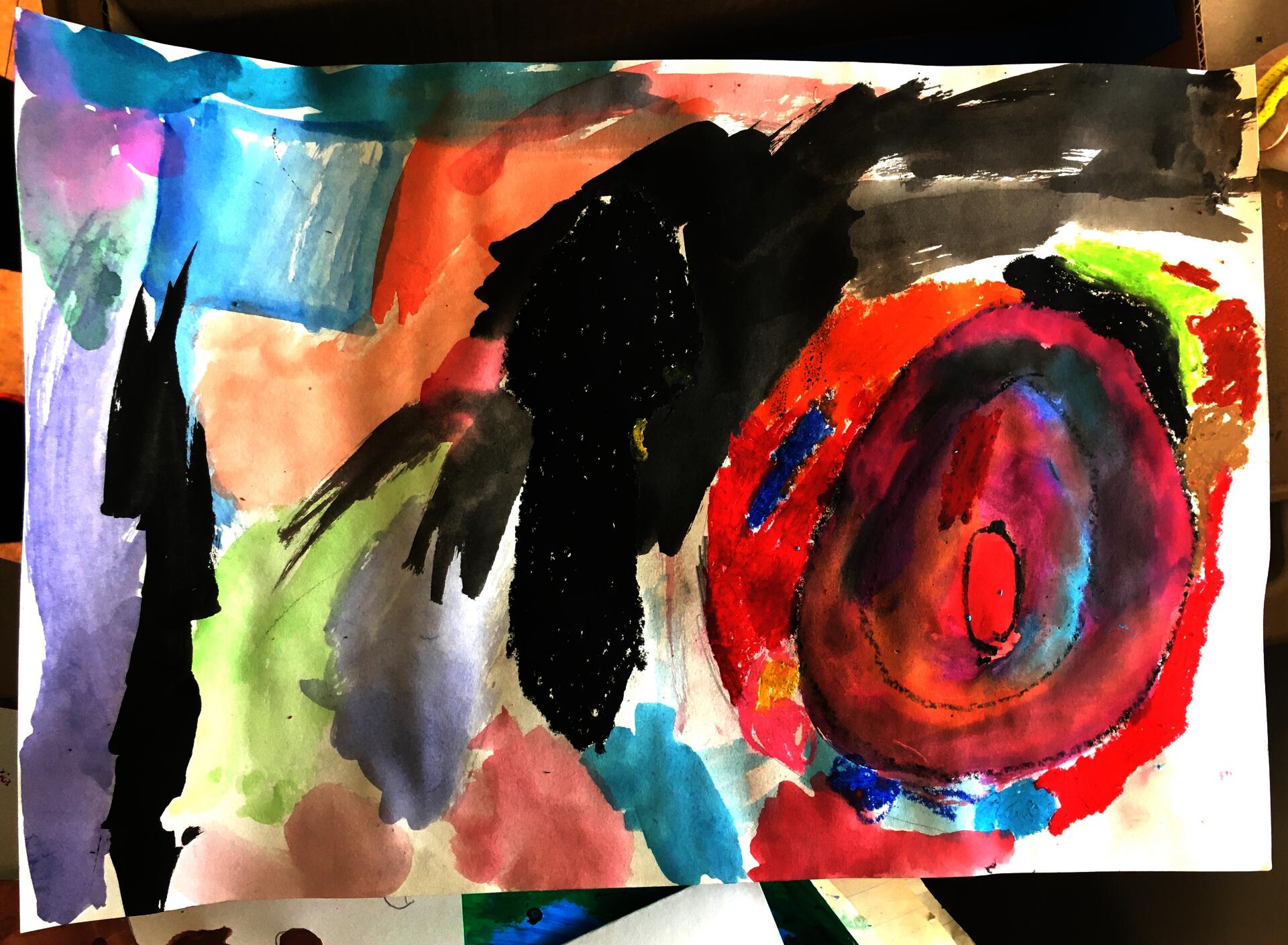 An in progress artwork of a wide black spoon drawn in oil pastel next to a plate drawn with oil pastel and filled in with pink watercolor with other hues blended in. Colored splotches of oil pastel are circling the edges of plate and the rest of the page is filled with wispy watercolor except the bottom right corner which is left white for now.