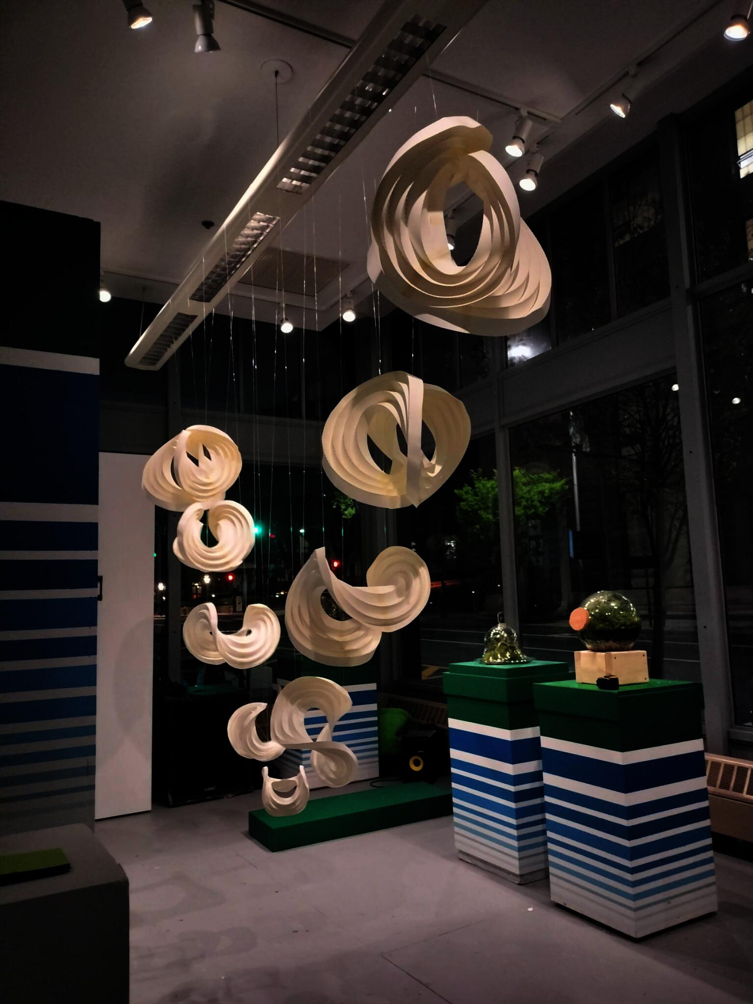Suspended curved paper sculptures of varying sizes and heights.
