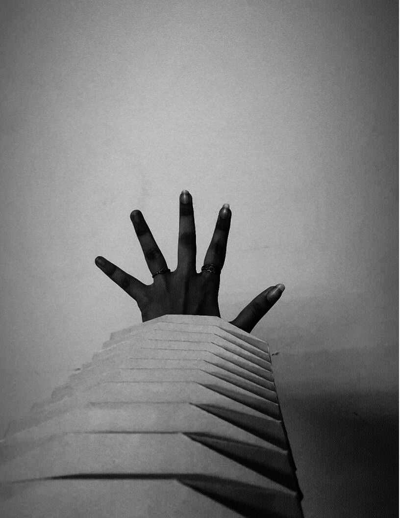 A folded sculpture with a palm reaching out of it.