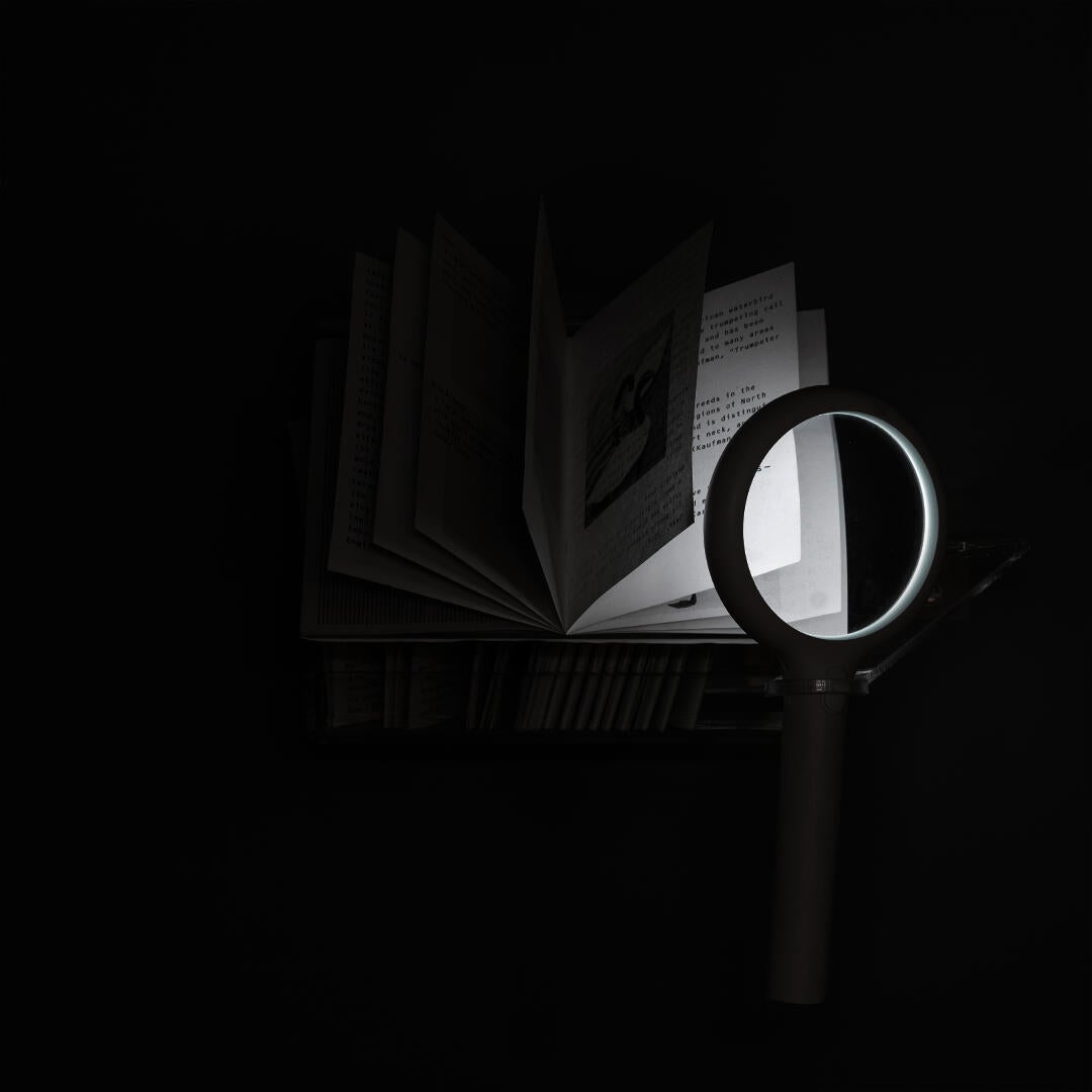 A zine floats beneath a luminous magnifying glass.