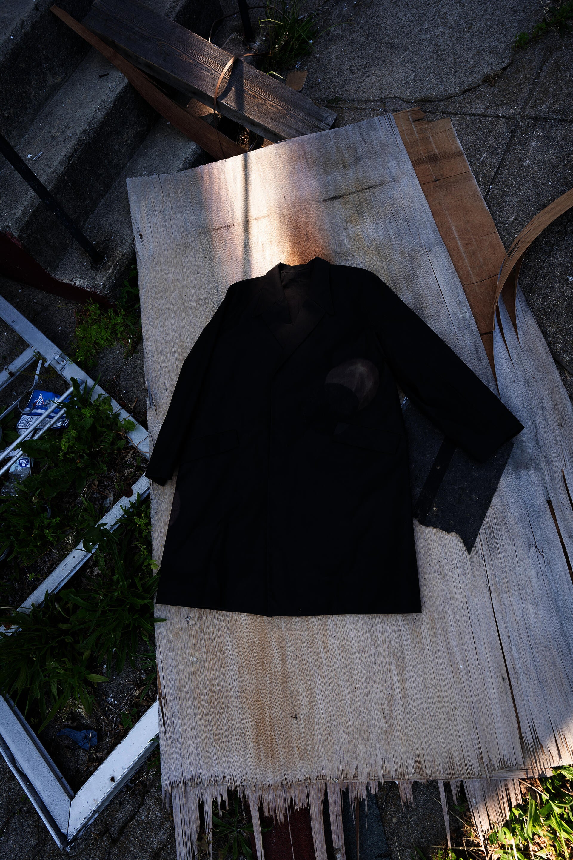 black coat on a piece of discarded wood on the ground
