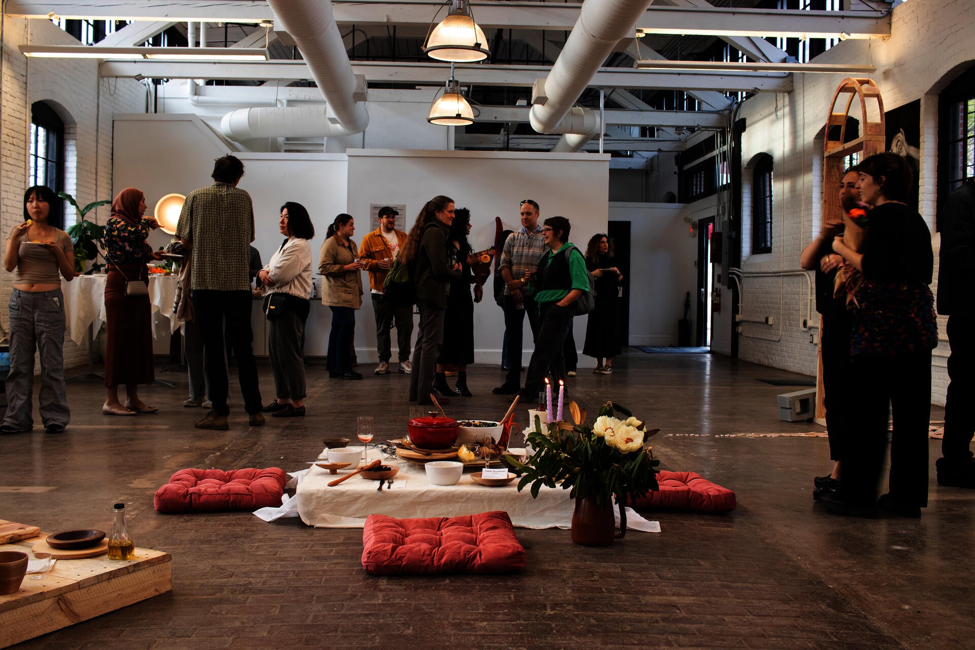 A low dining set up for four people in the middle of a gallery opening surrounded by people.