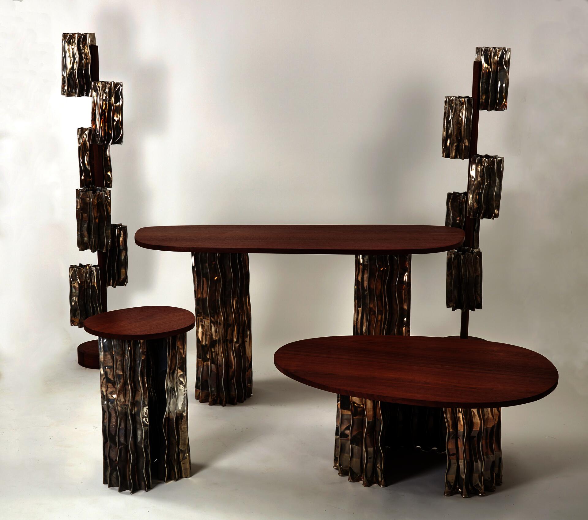 A modern furniture collection includes a coffee table, console table, pedestal table, and two floor lamps. The tables have an aluminum base and walnut tops. The floor lamps display decorative aluminum shades and central walnut stands.