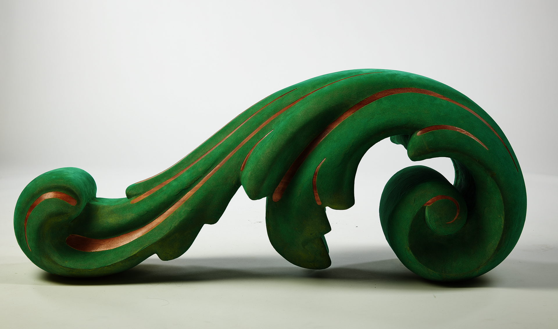 A large solid wood freestanding acanthus leaf ornament made of mahogany and coated in green flocking with detail linework exposing bare wood.