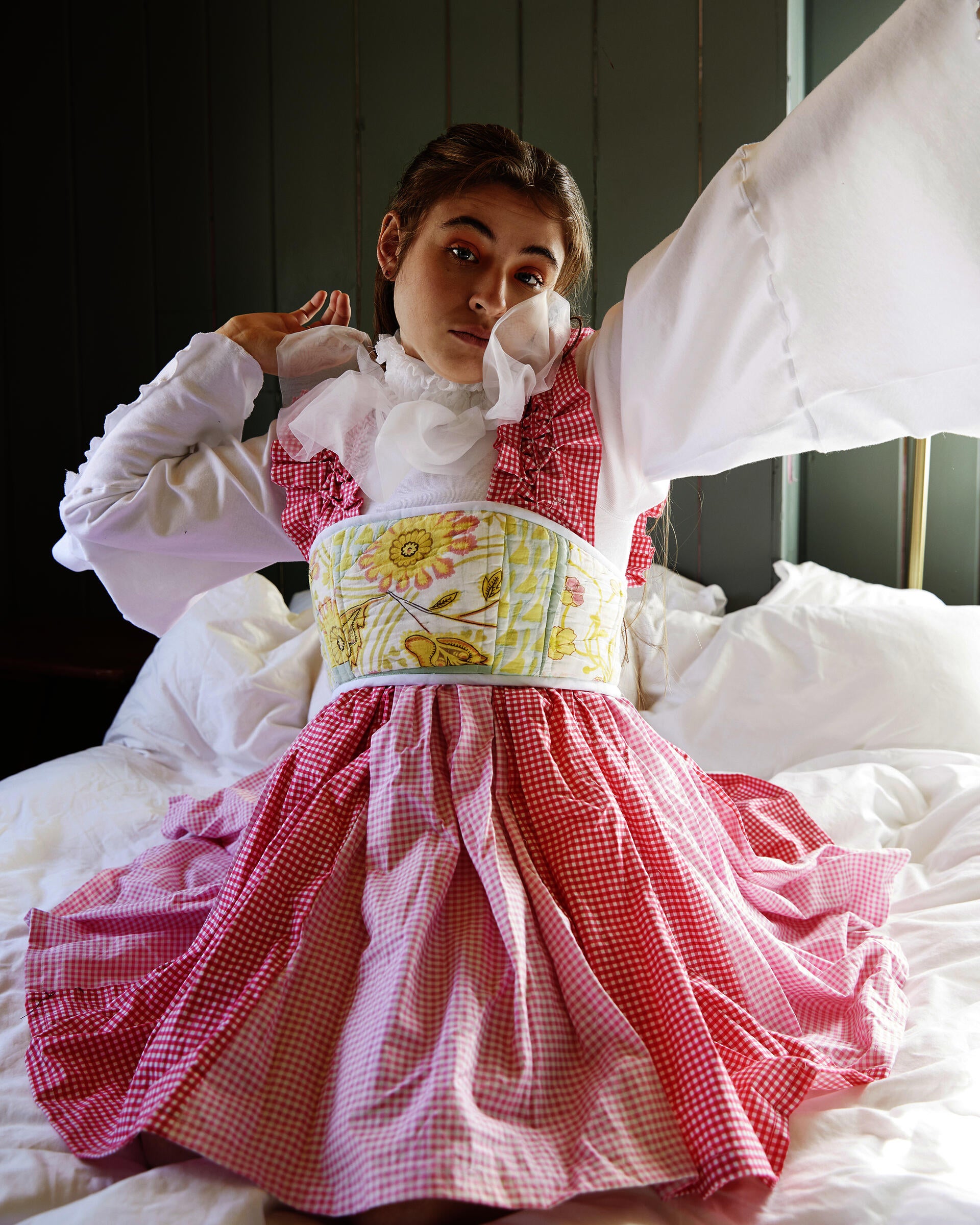 Girl stretching in pink gingham dress with floral green and yellow corset