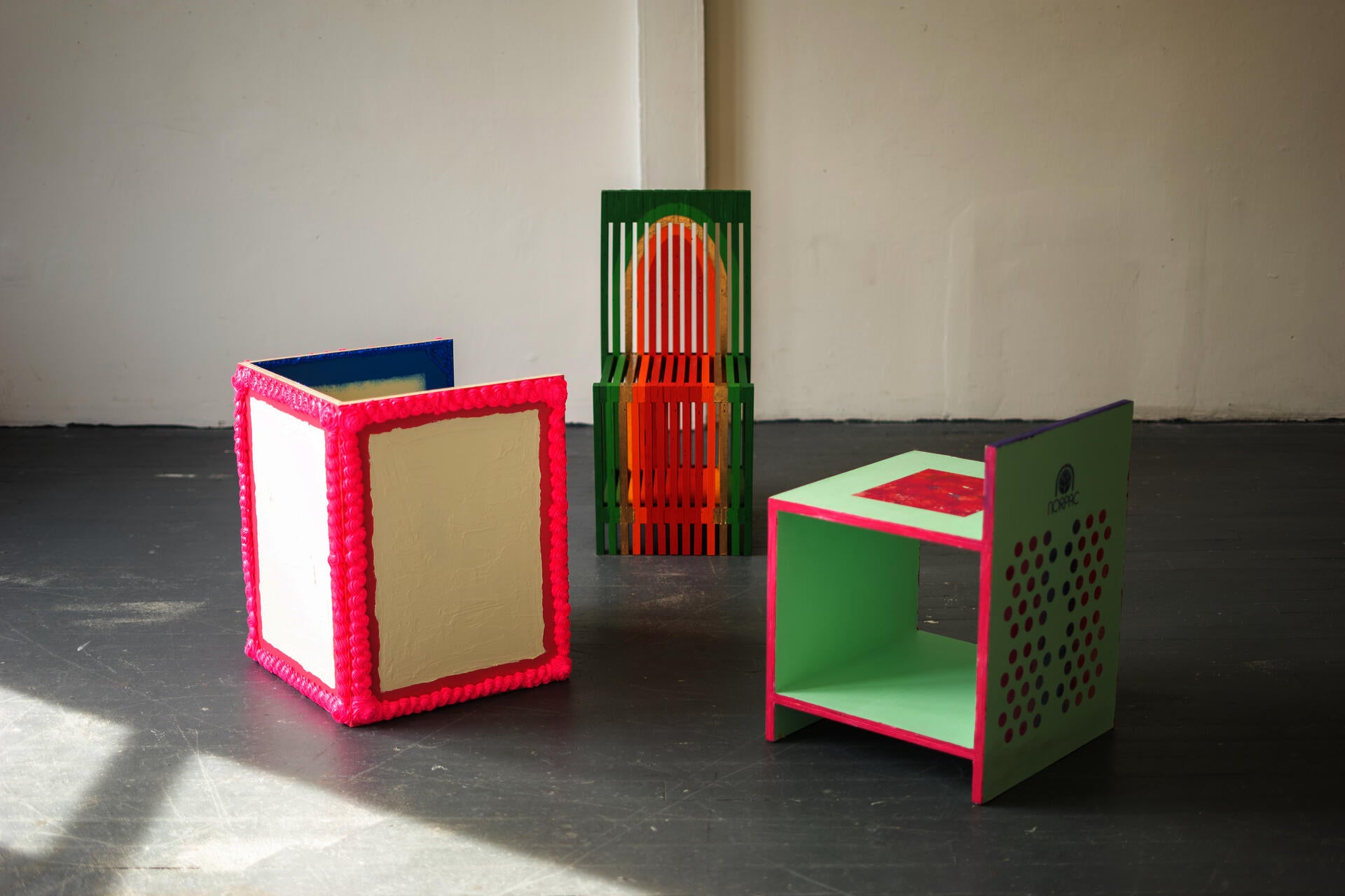 Three colorful ornamented chairs sit in the middle of a room.