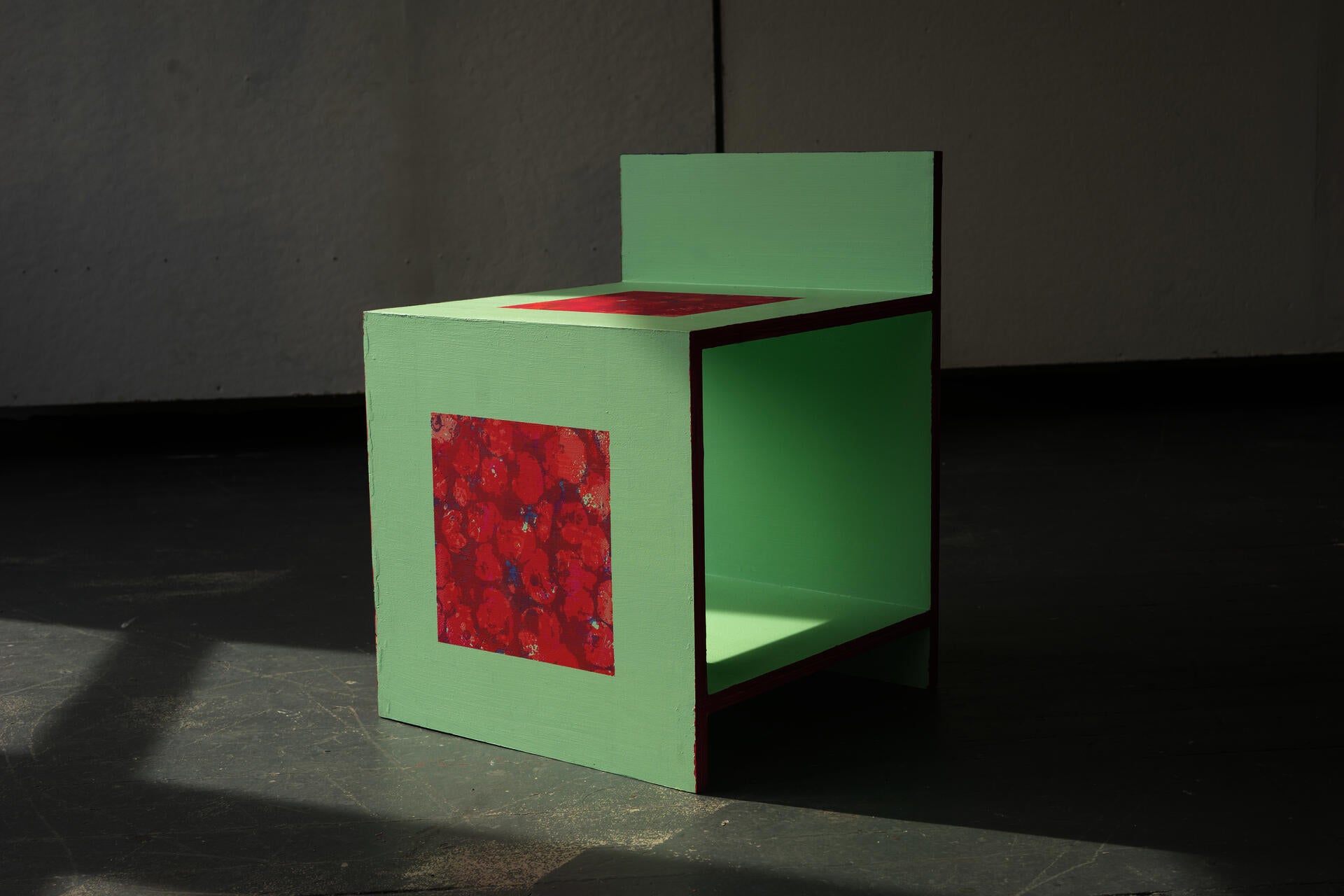 A minimalist press back chair with berry-colored print patterns on the faces.