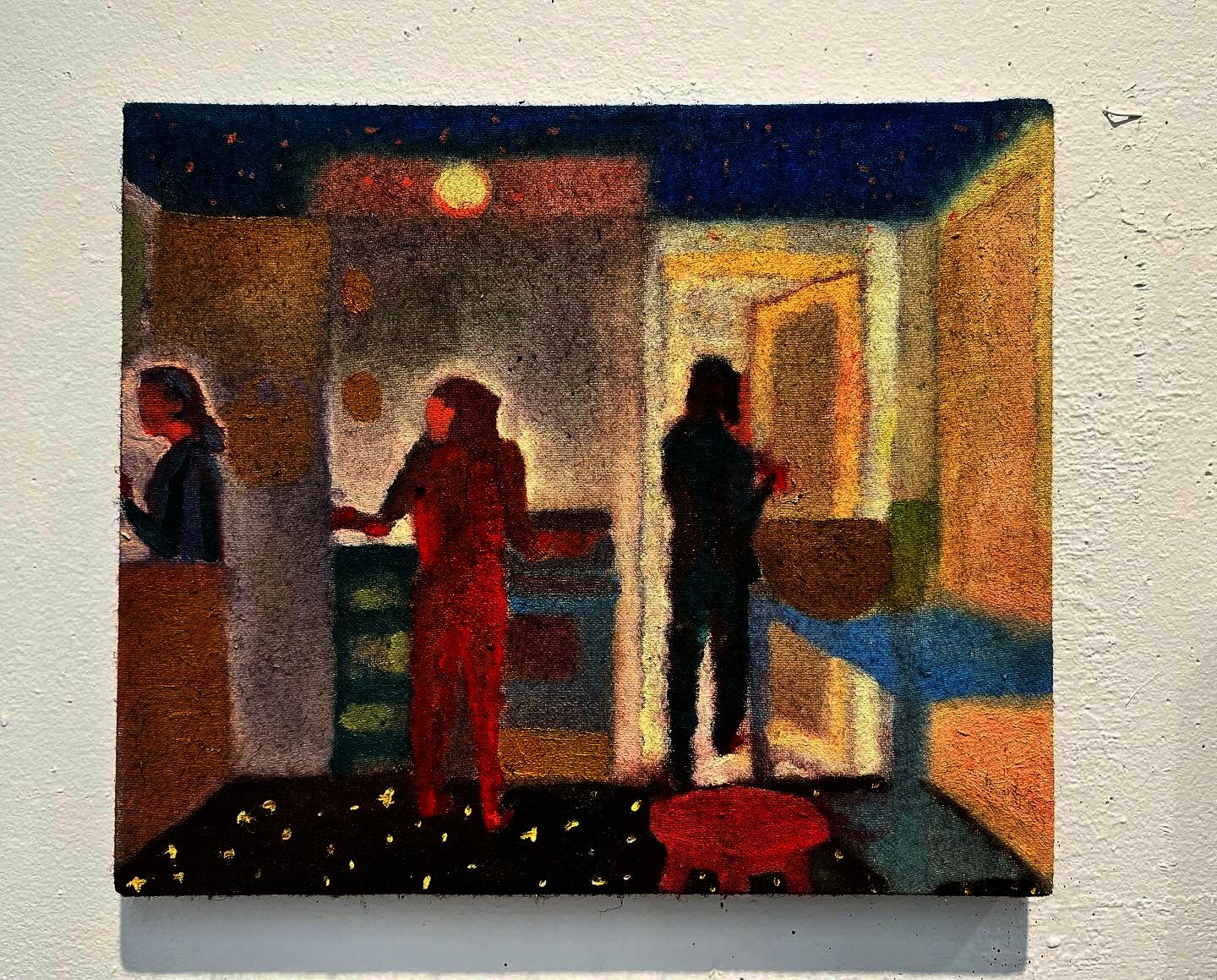 Three people standing in various positions in a interior view of a kitchen.