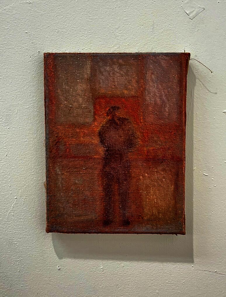 View of a person from behind washing dishes at a sink. The atmosphere is hazy and warm.
