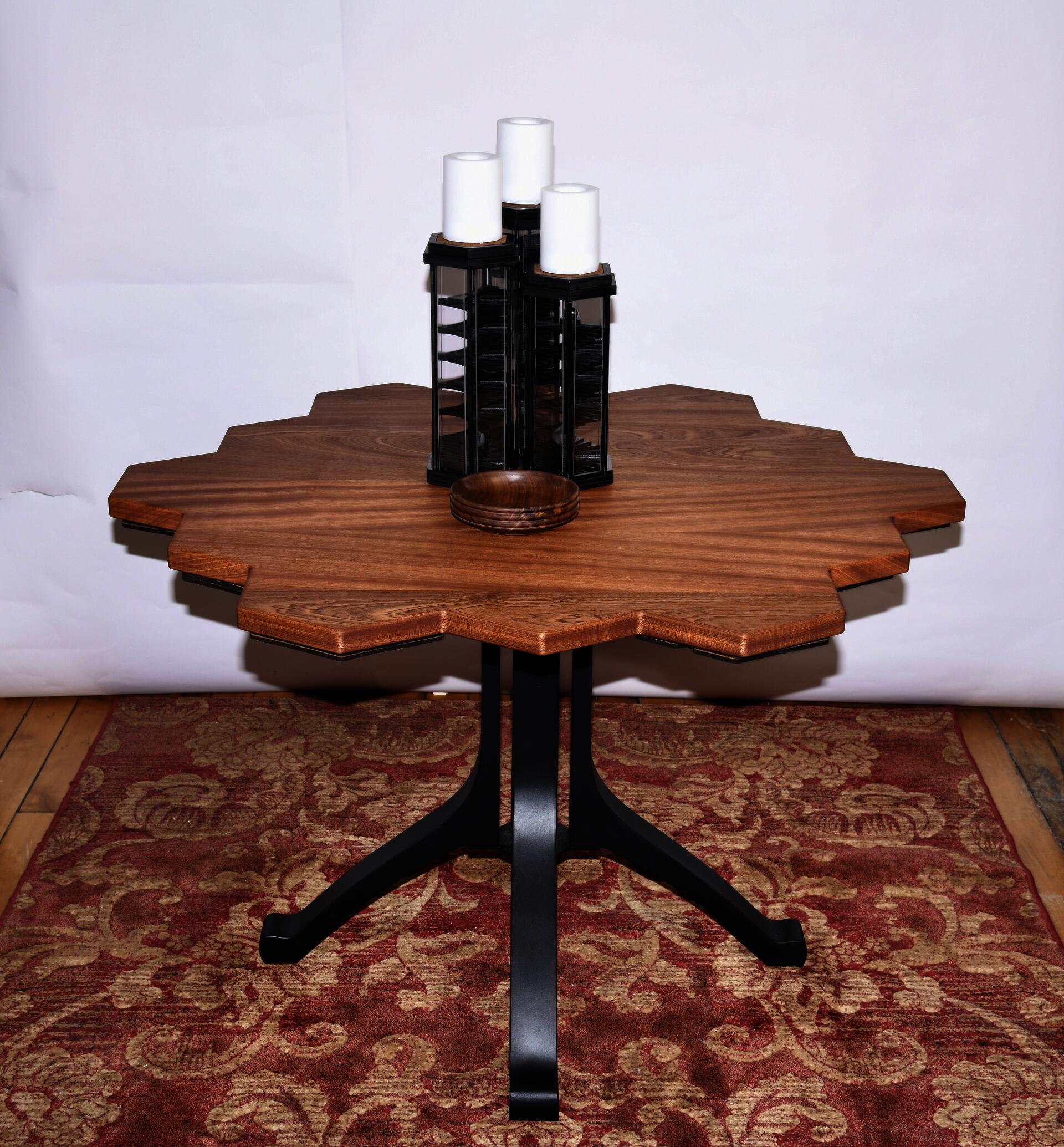 Wood table with three hexagonal candle sticks on top. A bowl on the hexagonal table. Woodeb table top metal legs. Honeycomb table shape.