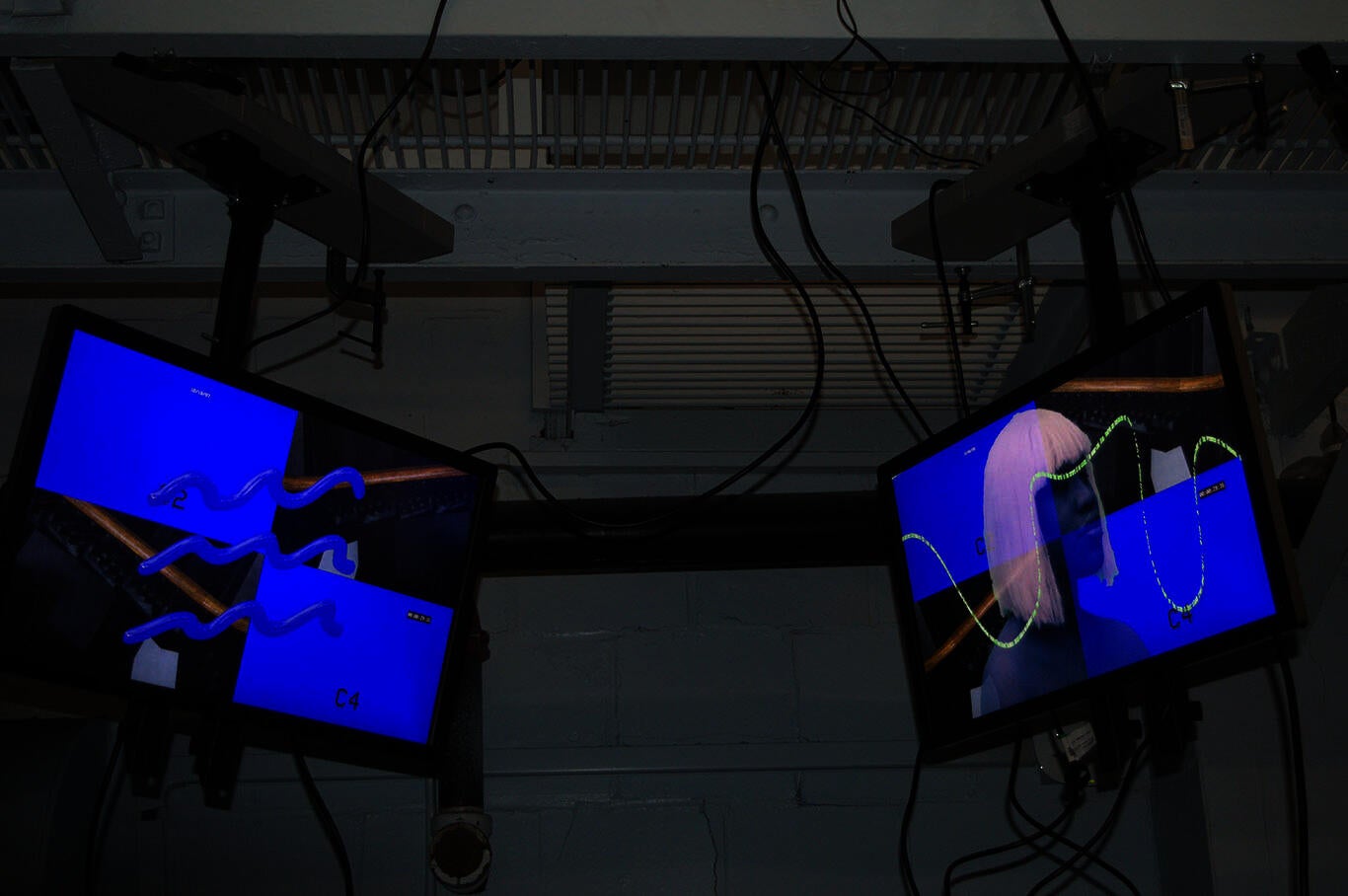 Two ceiling-mounted screens show a deep violet wave symbol (left) and a blue figure with white hair (right). Both have a background resembling a four-panel security monitor.