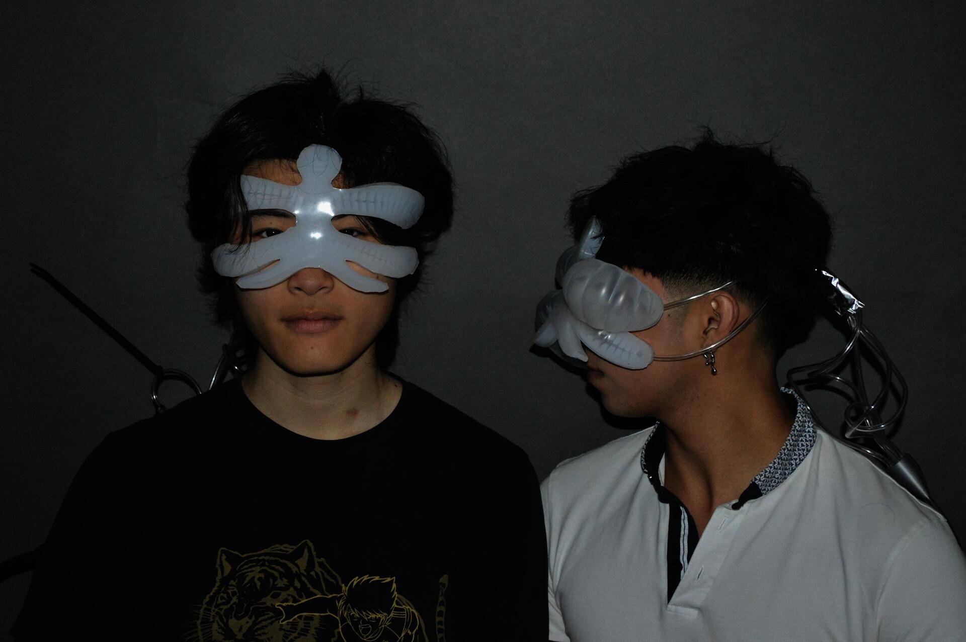 Dylan and Brandon. Dylan is looking into the camera, with chimera not reacting - and Brandon is looking at them with their augmentation inflated. This shows that Brandon is having an emotional response while Dylan is in a neutral state. 