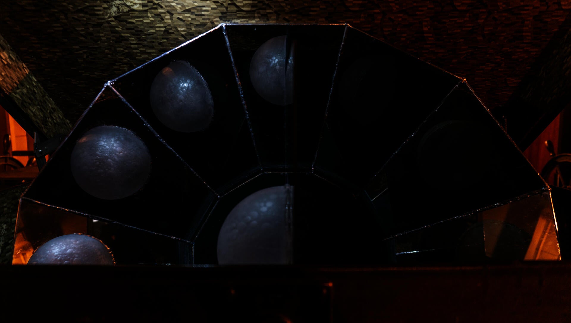 In an antique suitcase, a reflective device composed of multiple mirror structures is placed to showcase the various phases of the moon through a semi-circular glass moon at the center.