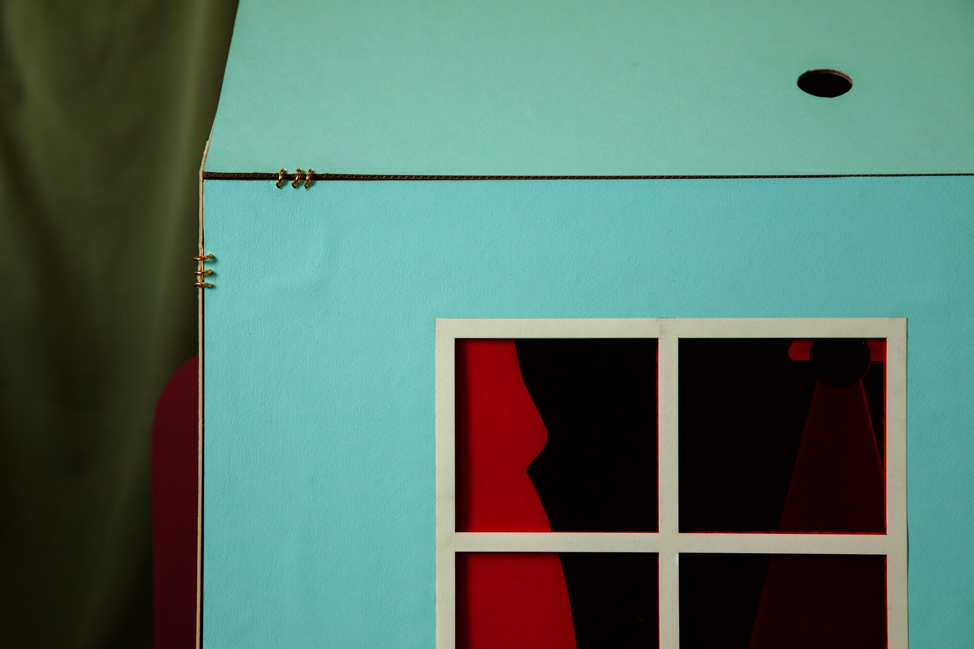 View of the facade of a house form depicting the day time sky with a window in red transparent material. 