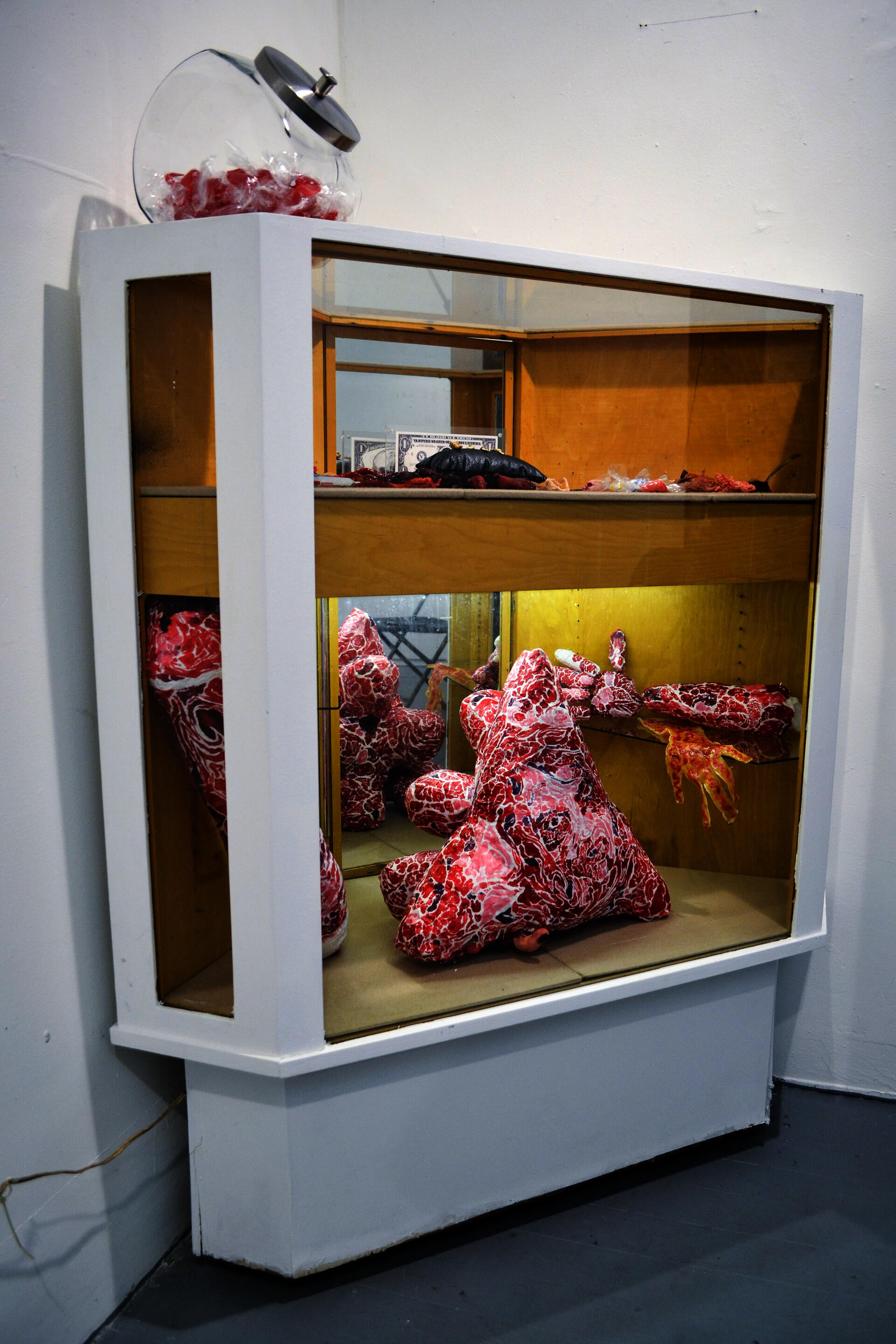 A corner jewelry display case with a variety of unusual items, including fake severed fingers and latex bloody sculptures. 